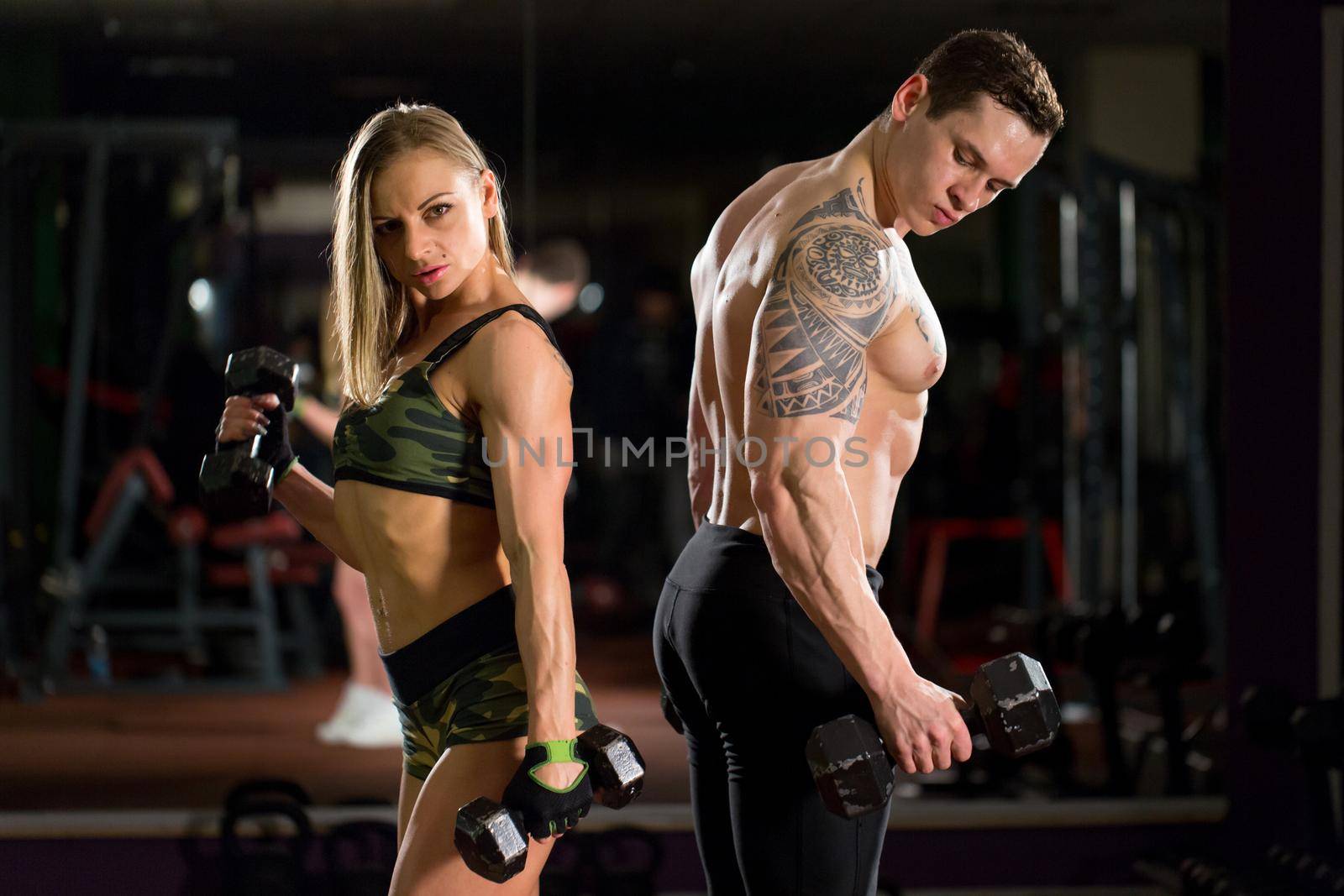 Beautiful young sporty sexy couple showing muscle and workout in gym. by StudioPeace