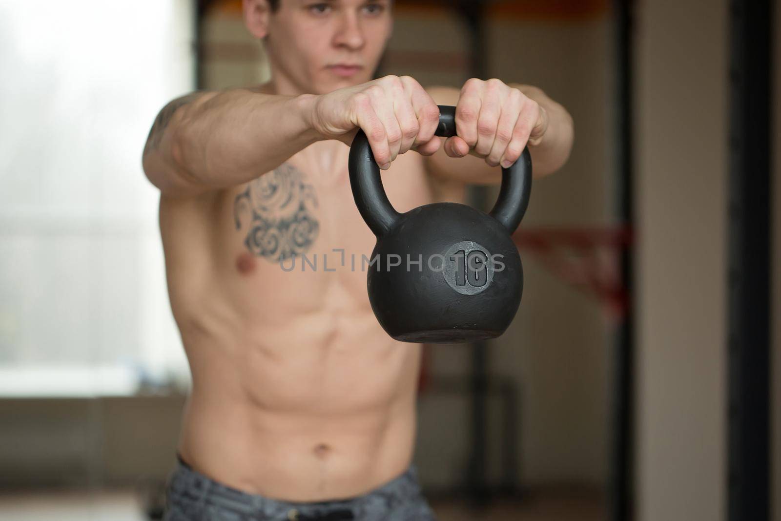 Beautiful man squats with kettlebell at the gym. by StudioPeace