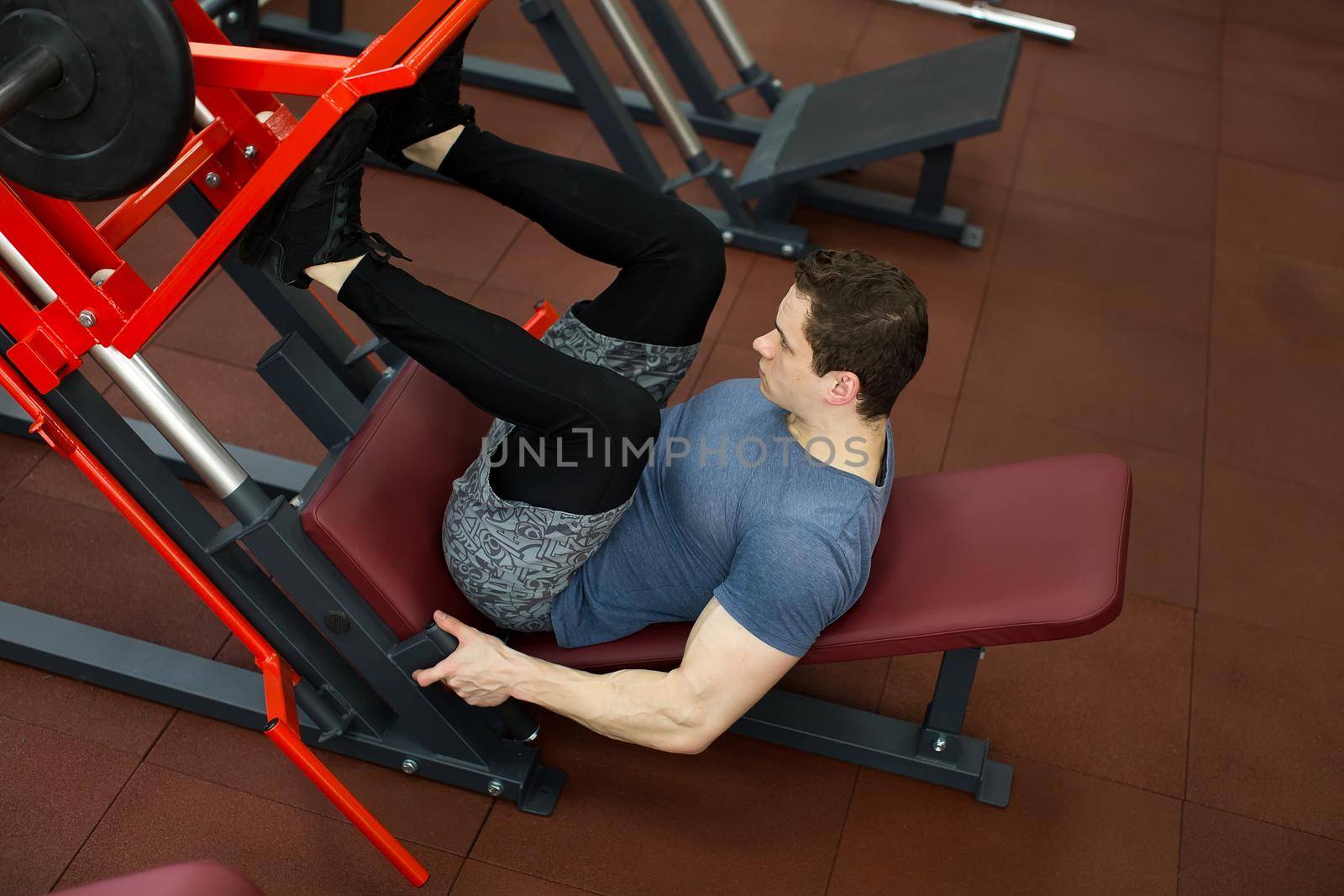 Attractive Young Man Doing Leg Press On Machine In Gym. by StudioPeace