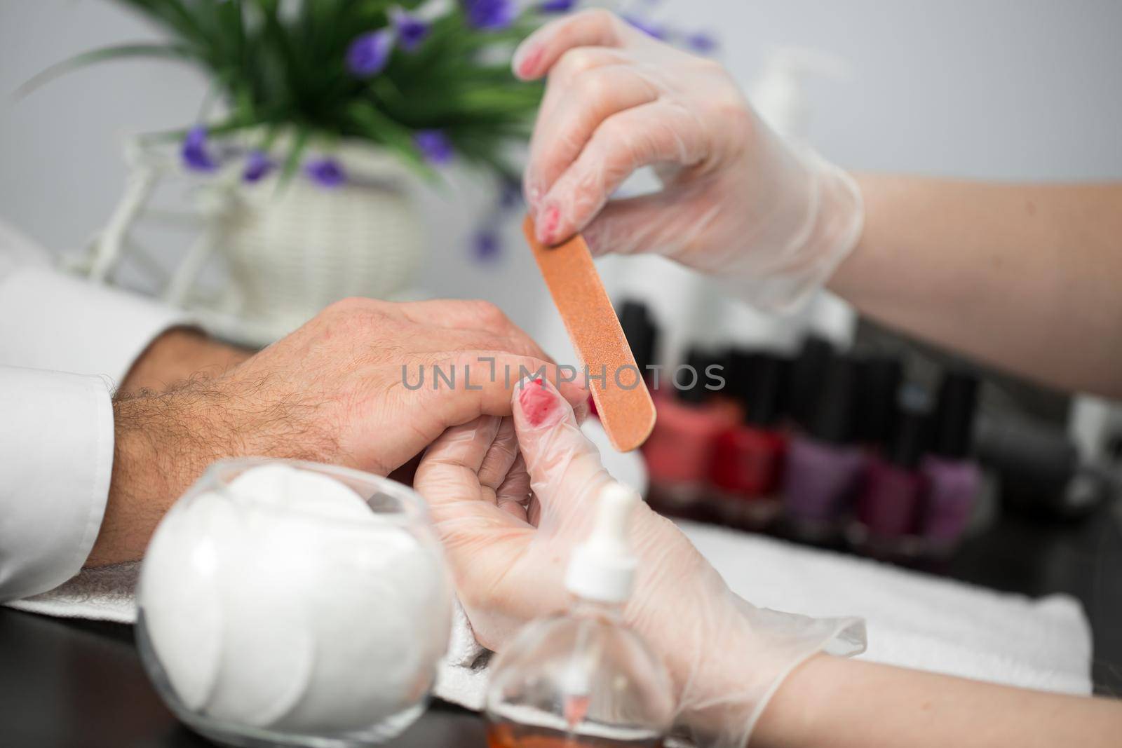 Girl manicurist doing manicure for man in beauty salon. by StudioPeace