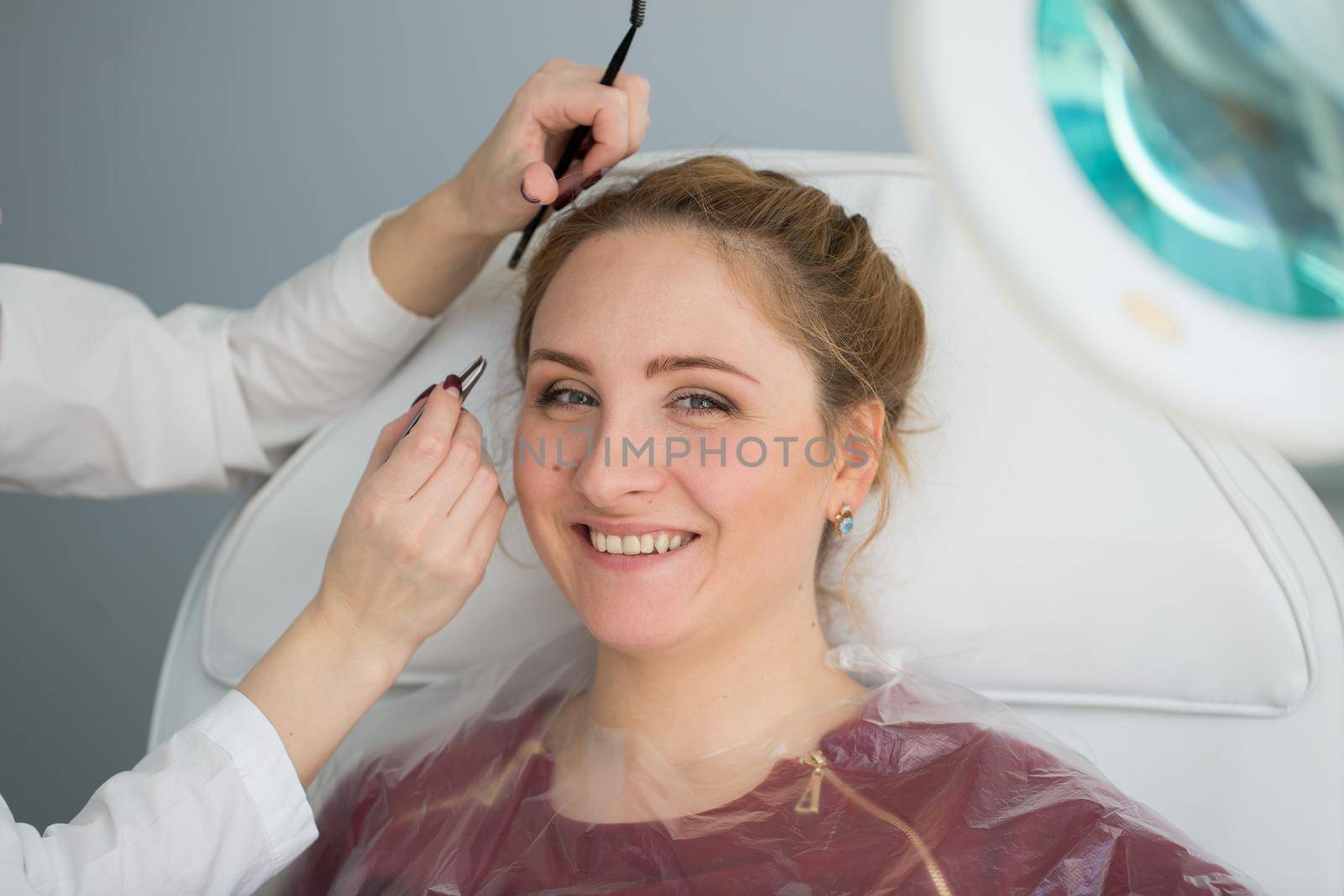 Plucking eyebrows by a cosmetologist in the salon. Isolated.