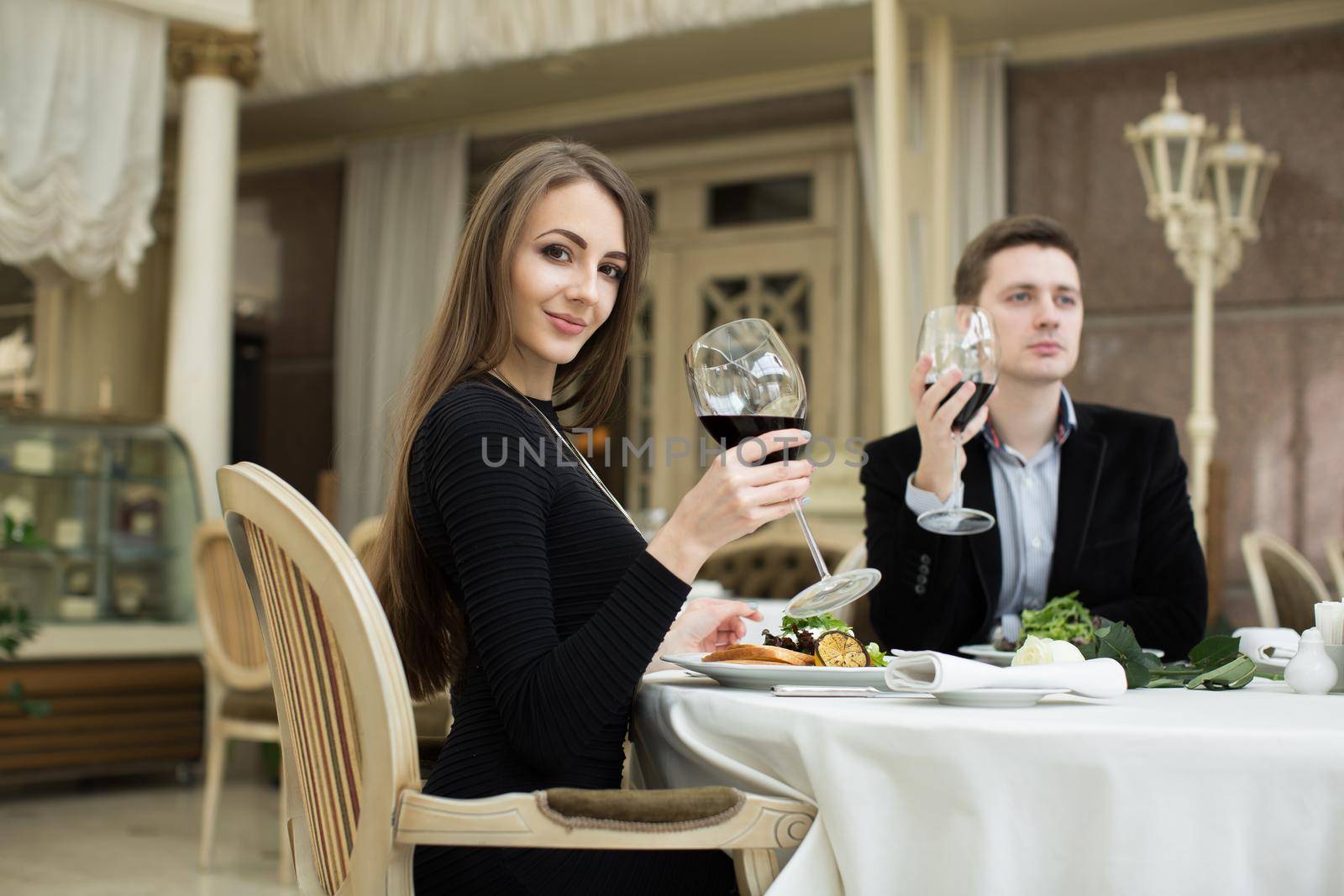 Beautiful woman and man in restaurant, holding glass of wine. by StudioPeace