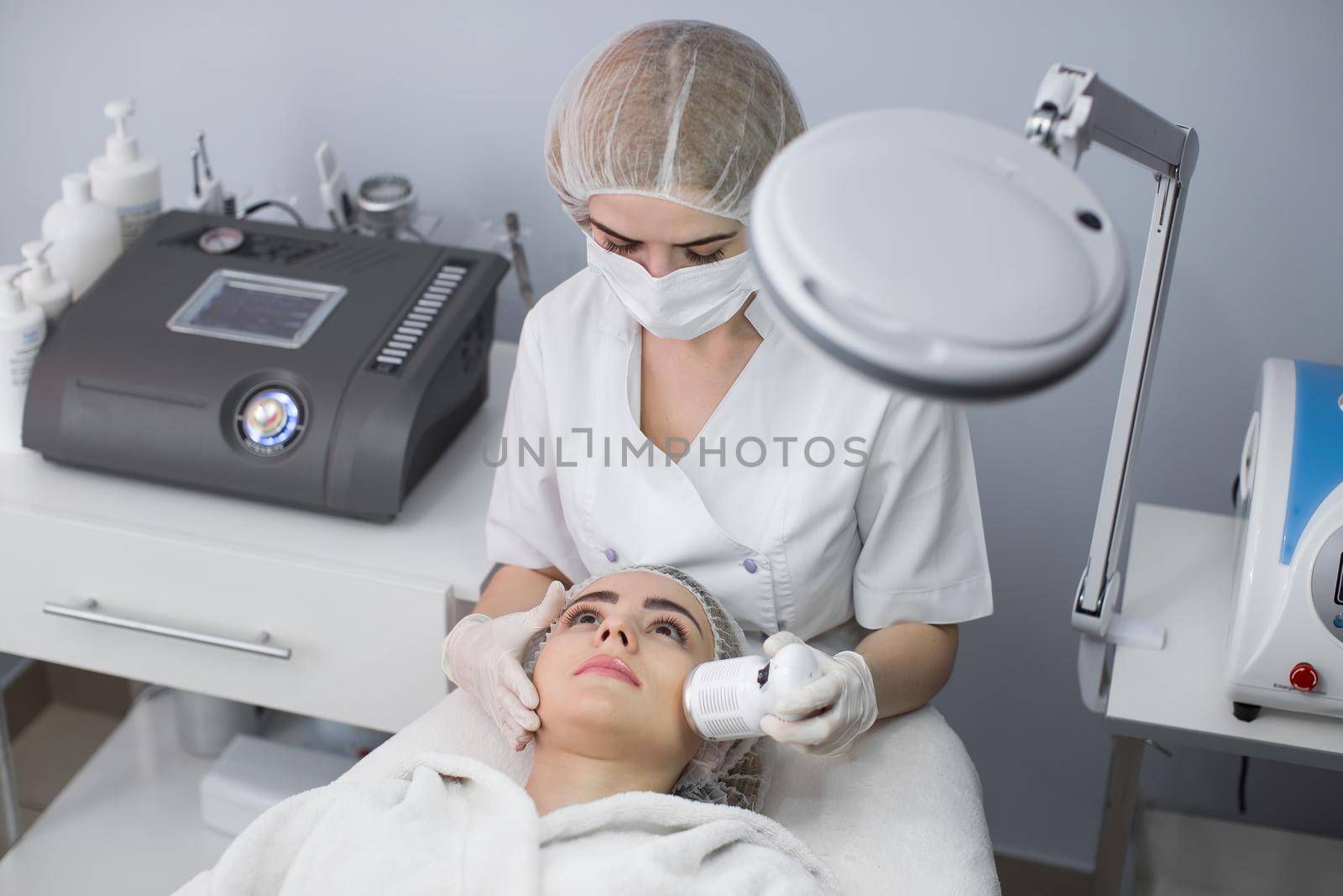 Cosmetology. Beautiful Woman Receiving Facial Skin Ultrasound Cavitation. Closeup Of Female Face Receiving Anti-Aging Cosmetics Using Ultrasound Cavitation Machine. Body Care. by StudioPeace