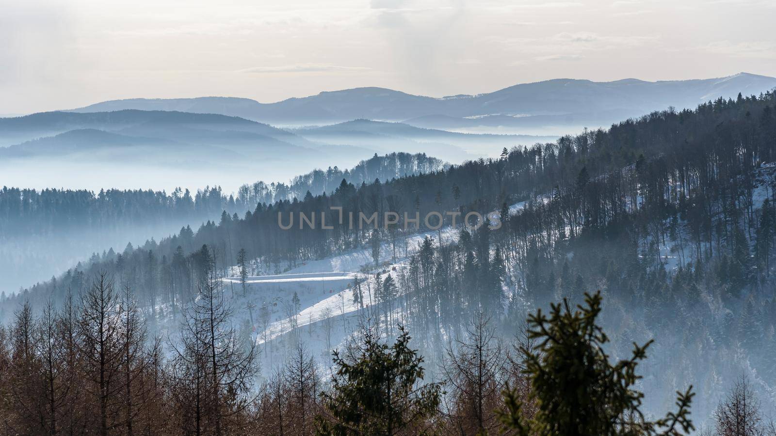 Foggy view of Beskid Sadecki mountain range with ski slope of Jaworzyna Krynicka in Poland