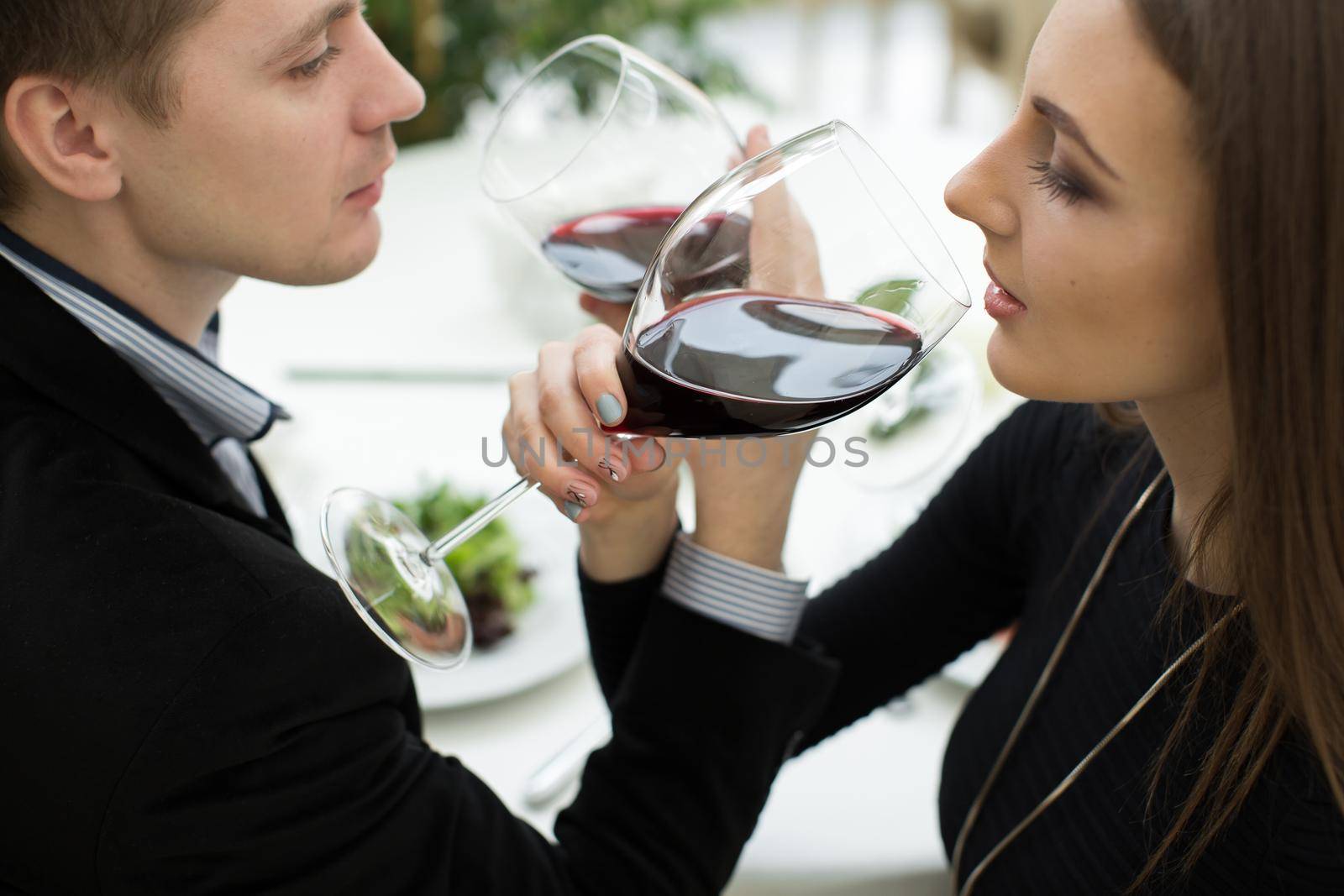 Young happy amorous couple celebrating with red wine at restaurant. Brotherhood