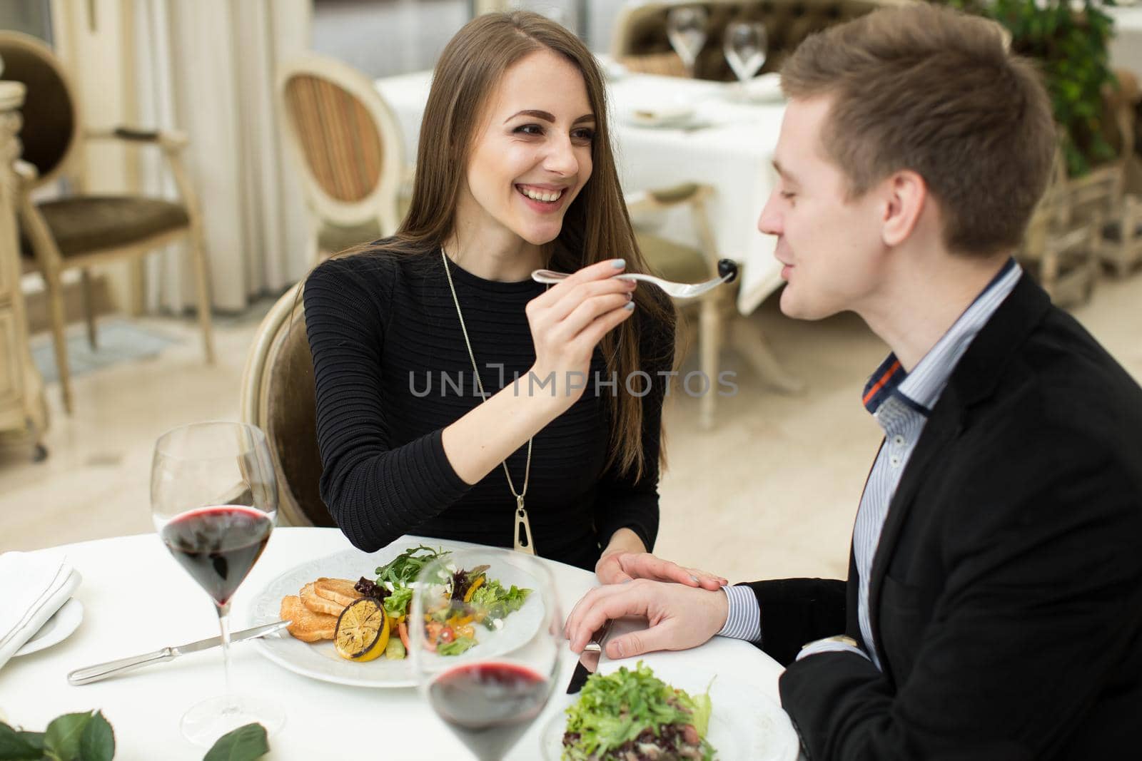 Beautiful young couple feeding each other and smiling while spending time at the restaurant