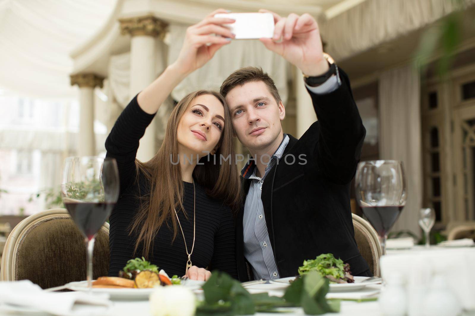 Beautiful couple taking selfie photo in a restaurant. by StudioPeace