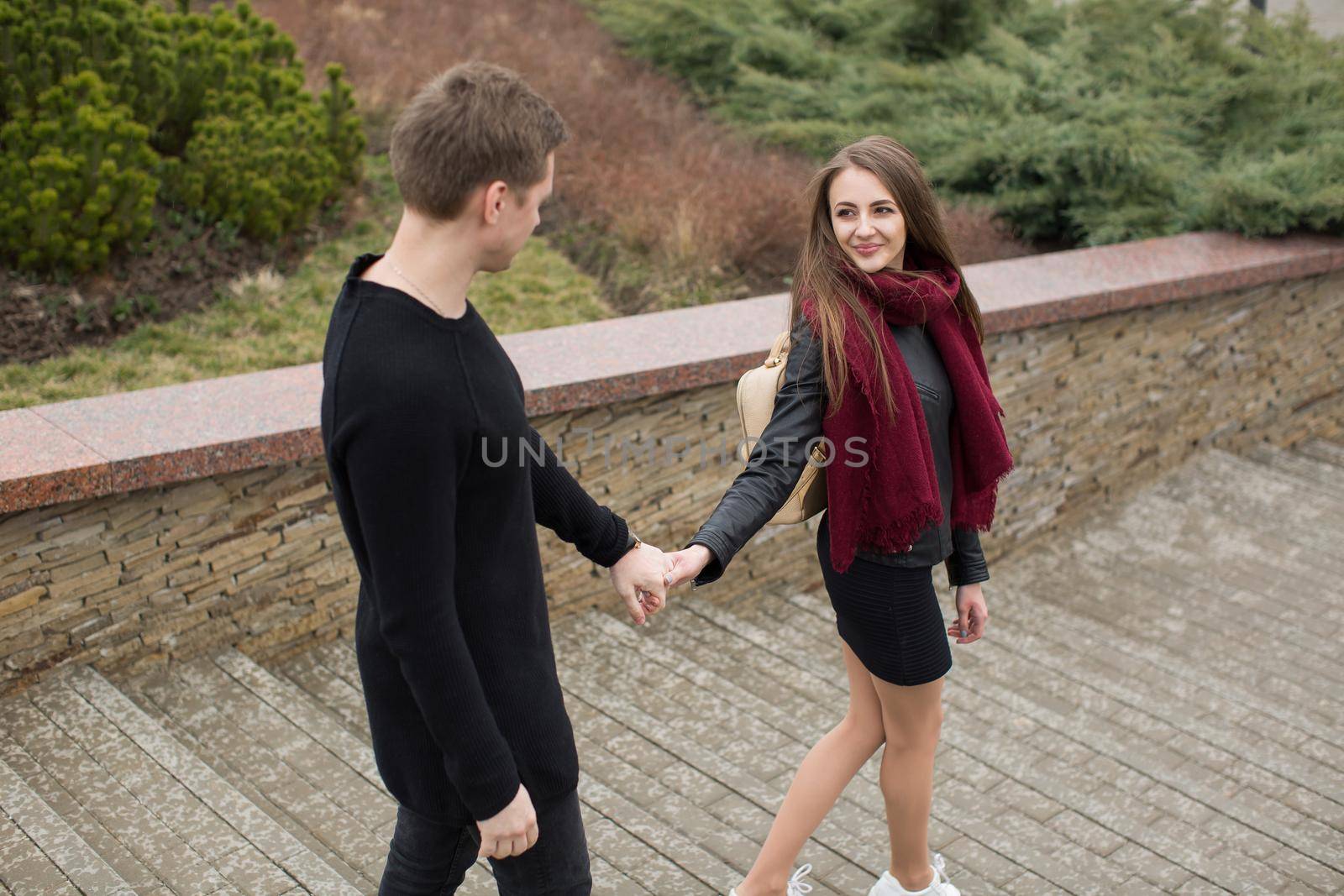 A beautiful woman and a man walk in the park by the hand