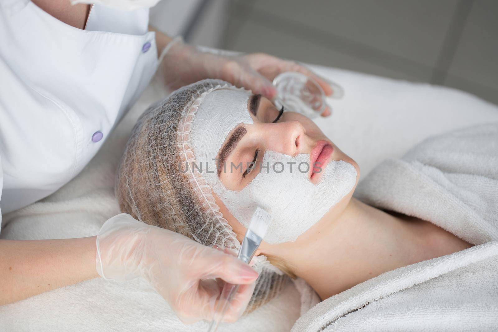 Face peeling mask, spa beauty treatment, skincare. Woman getting facial care by beautician at spa salon