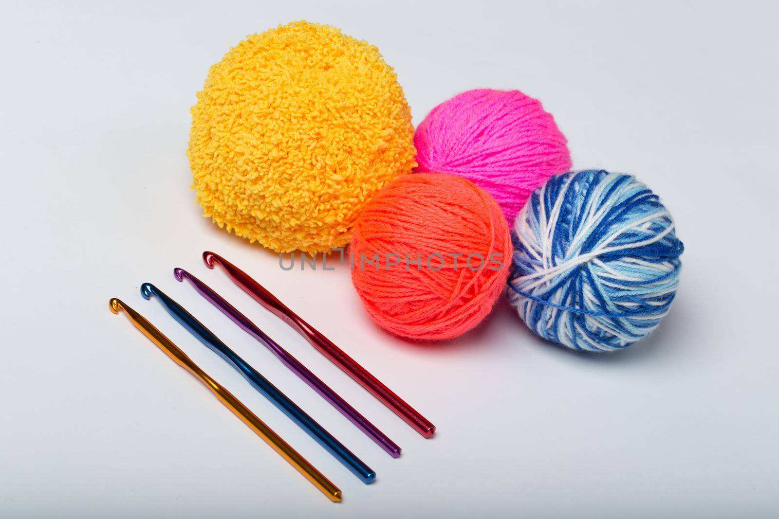 a group of multi-colored balls of yarn and knitting needles on a white background by StudioPeace