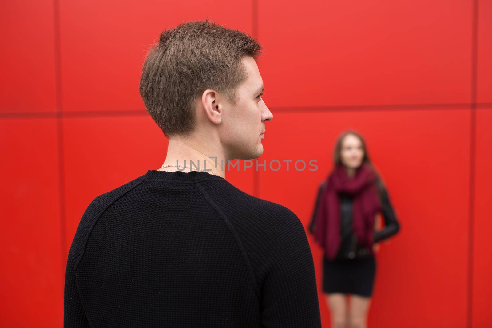 Young man and woman in passion, emotion, on the street with a backdrop of the red wall. Fashion. by StudioPeace