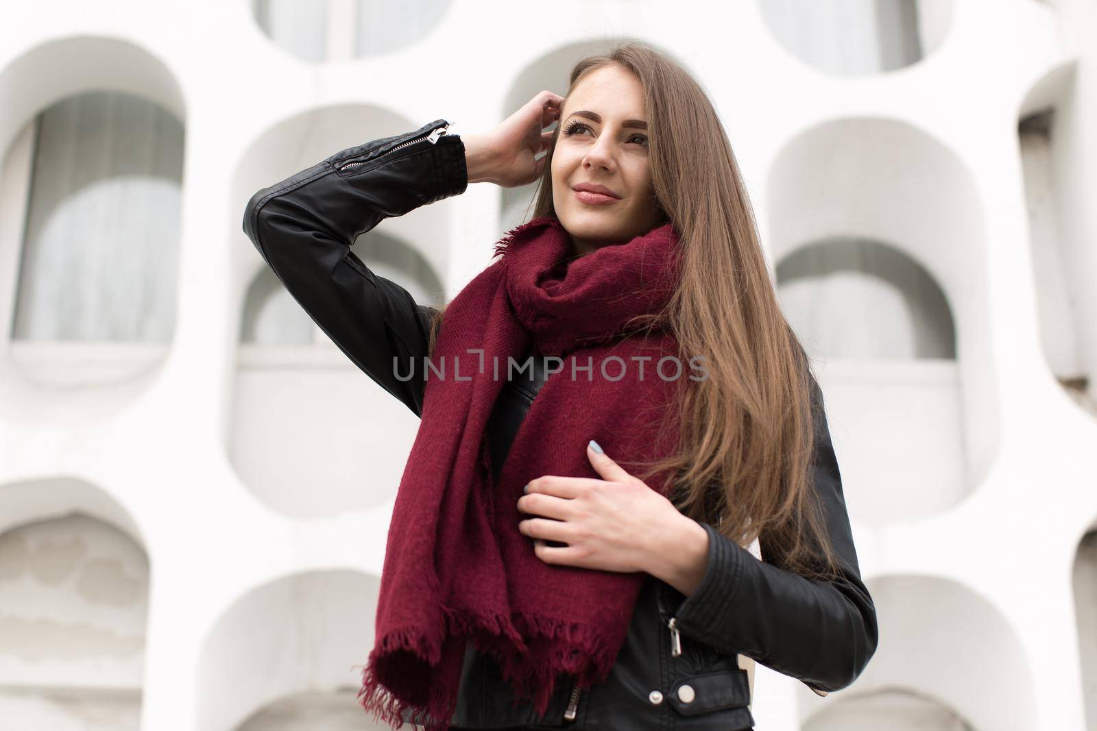 Fashion young woman in a black rock on a white wall background