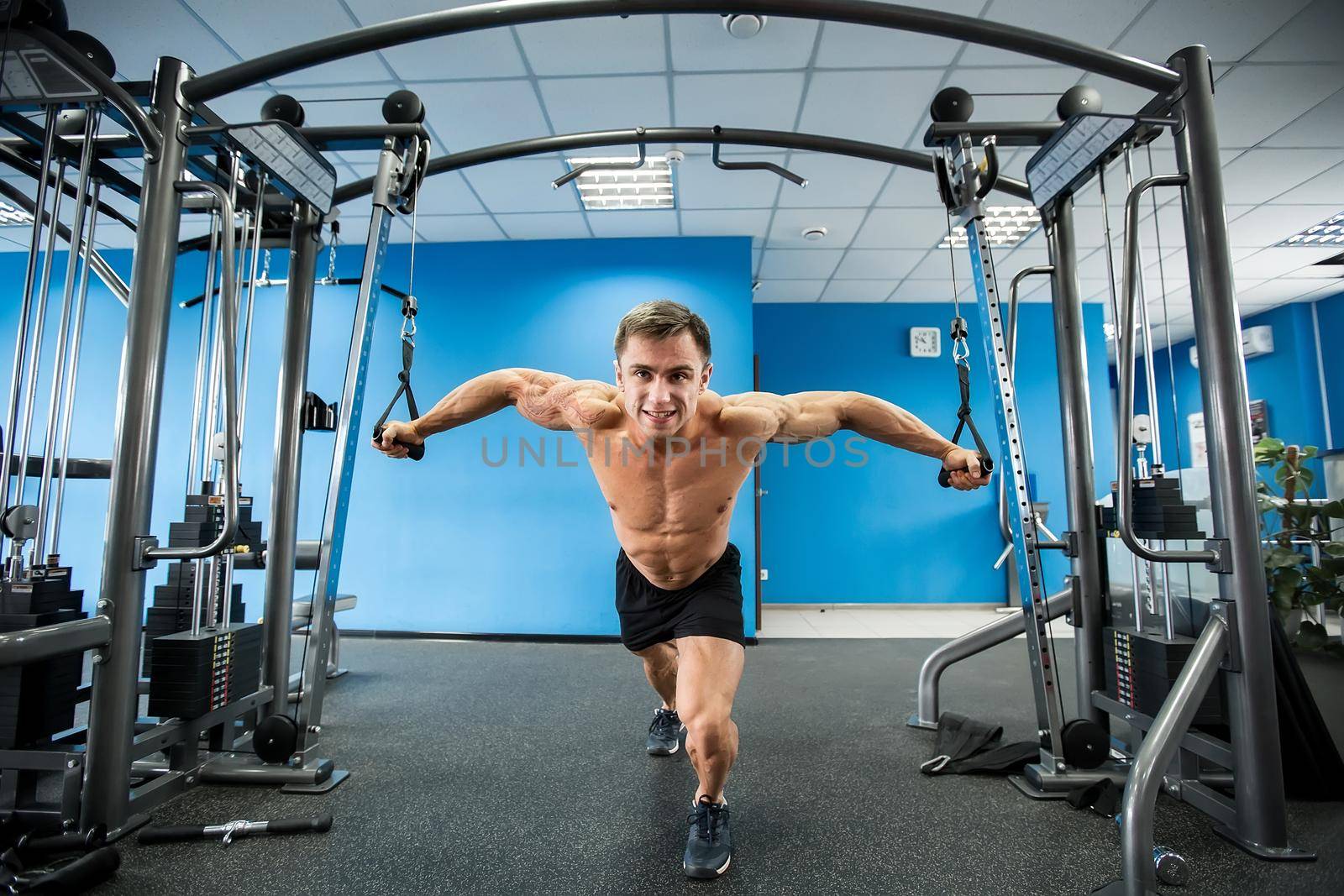 Young Bodybuilder Is Working On His Chest With Cable Crossover In Gym. by StudioPeace