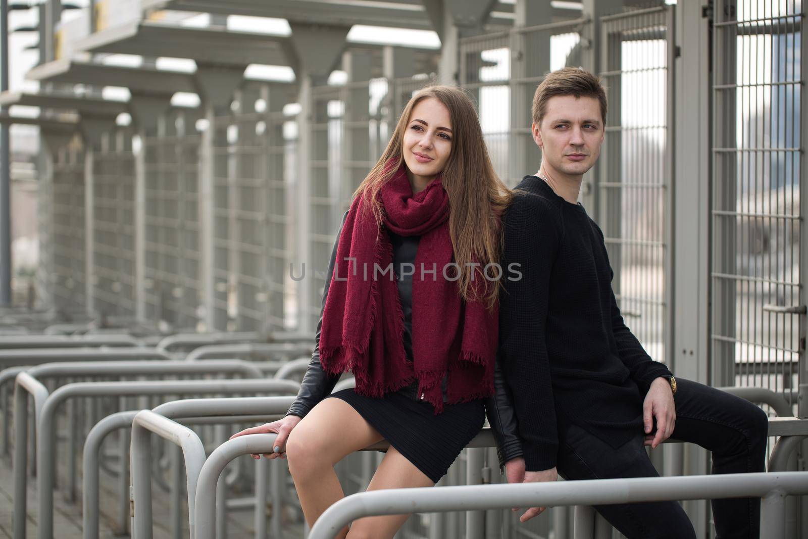 Young couple man and woman sitting on the railing. by StudioPeace