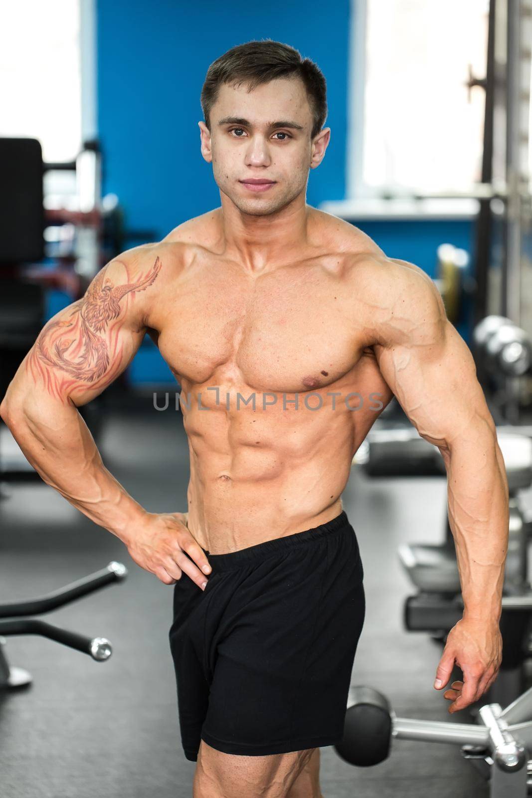 Bodybuilder posing for the camera in the gym. by StudioPeace