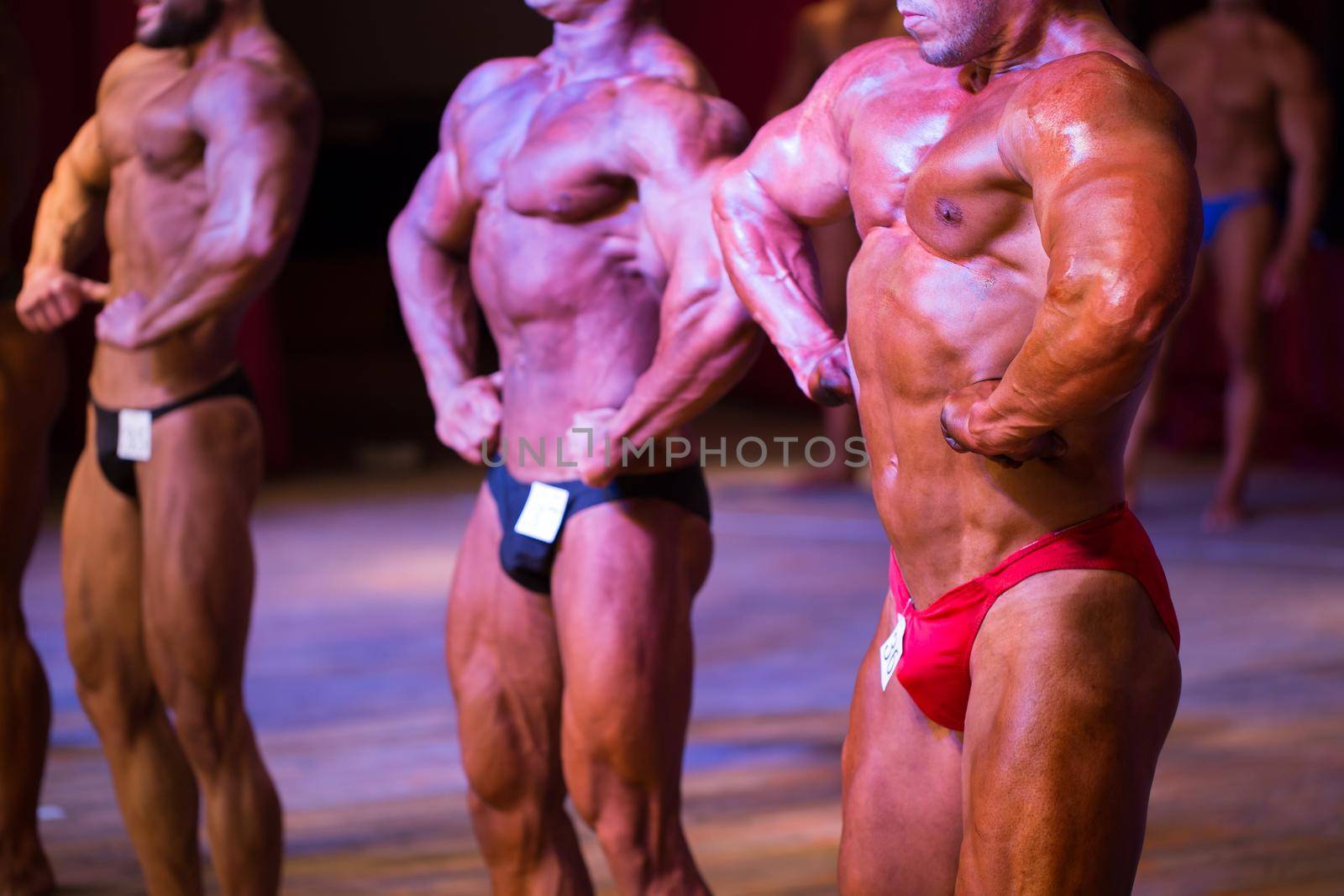 athlete bodybuilder demonstrates abdominal muscles and chest at competitions. by StudioPeace