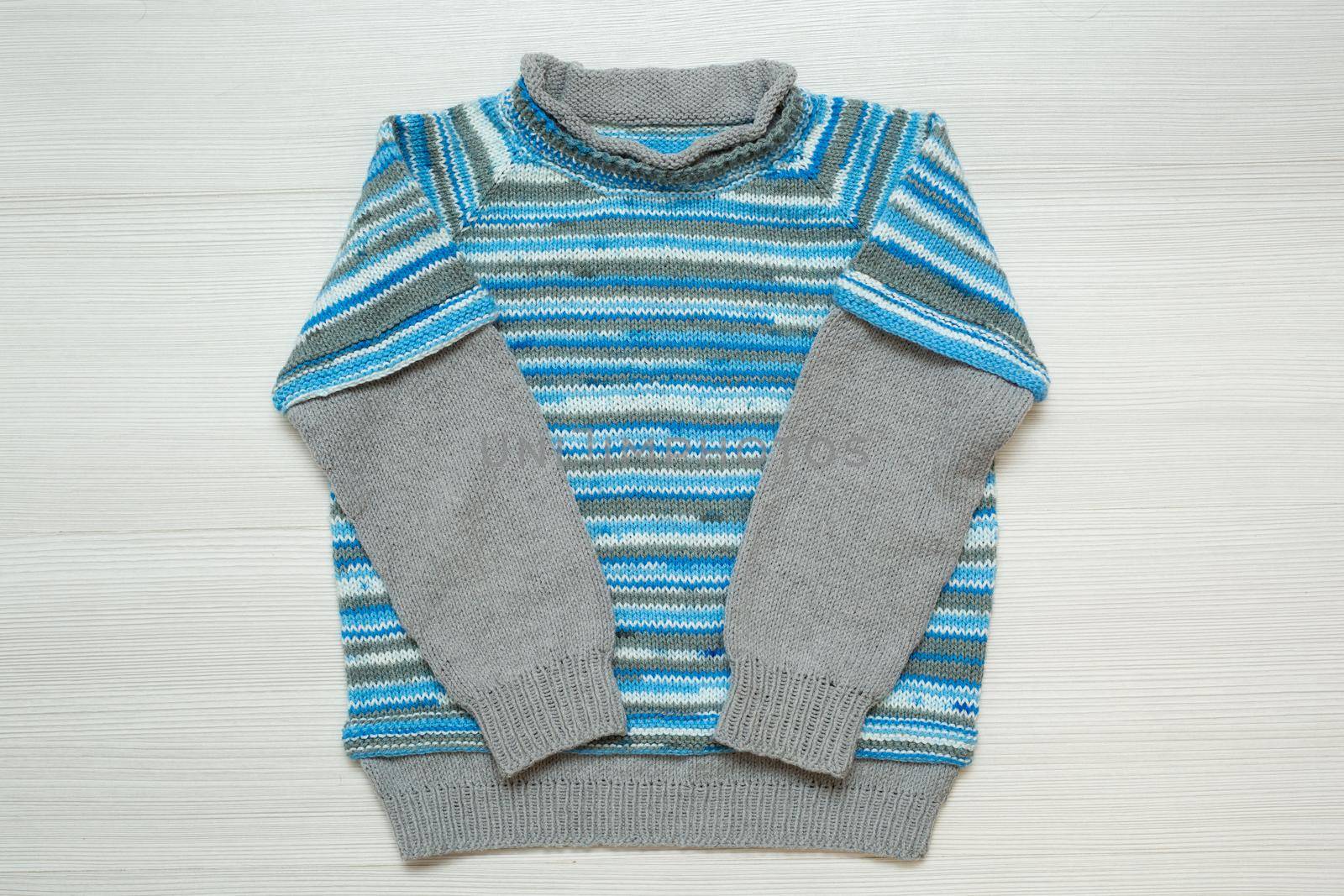 Knitted children's sweater on a white background. by StudioPeace