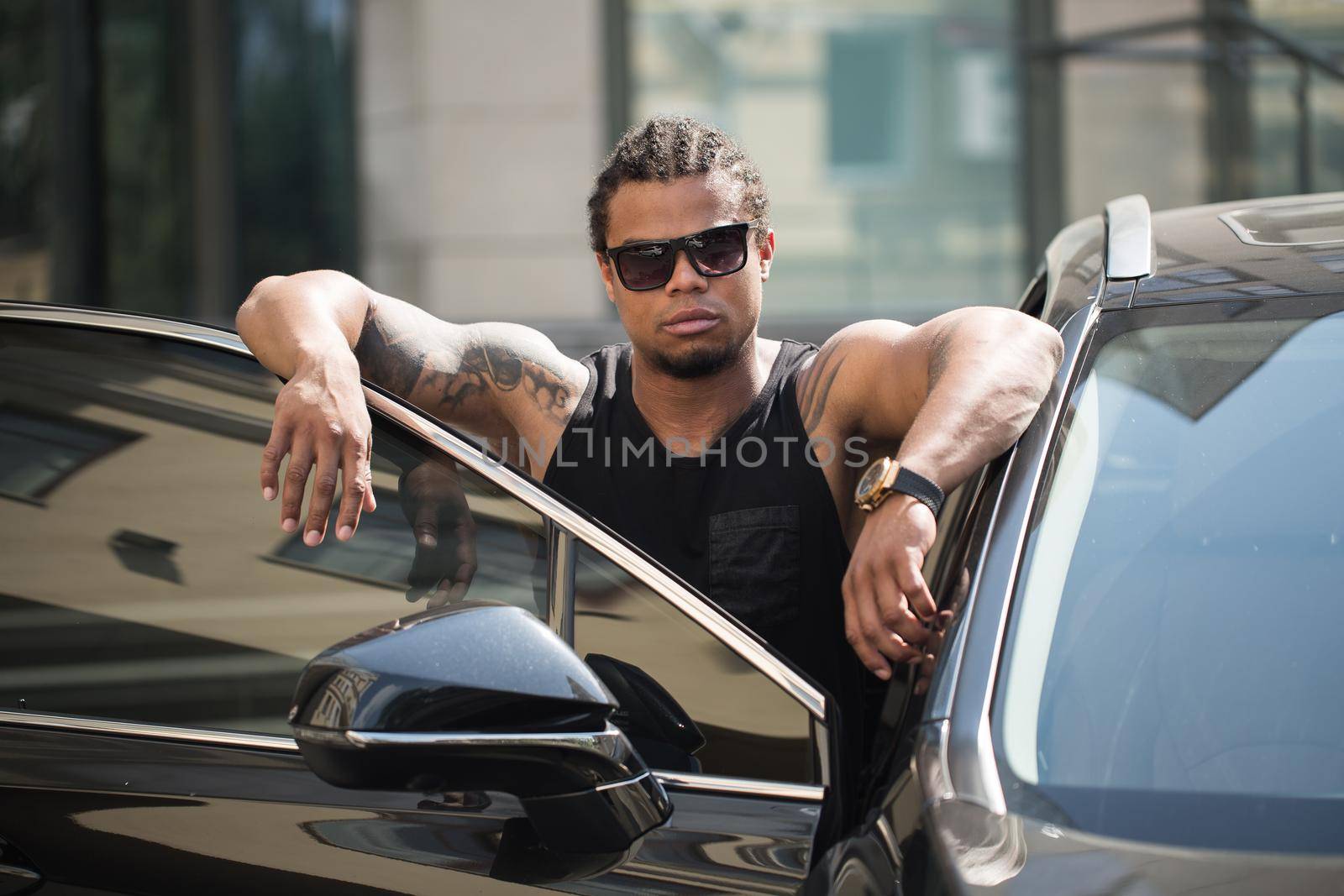 An African-American man poses near his car