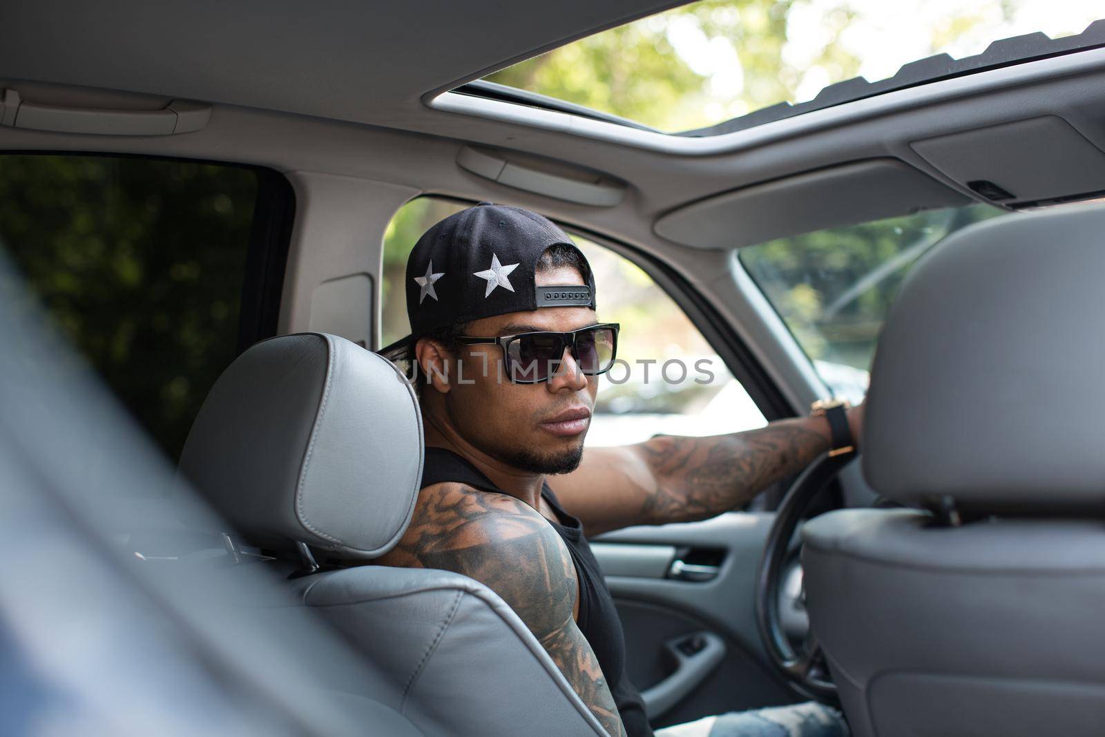 Stylish black man sitting behind the wheel of luxury car by StudioPeace