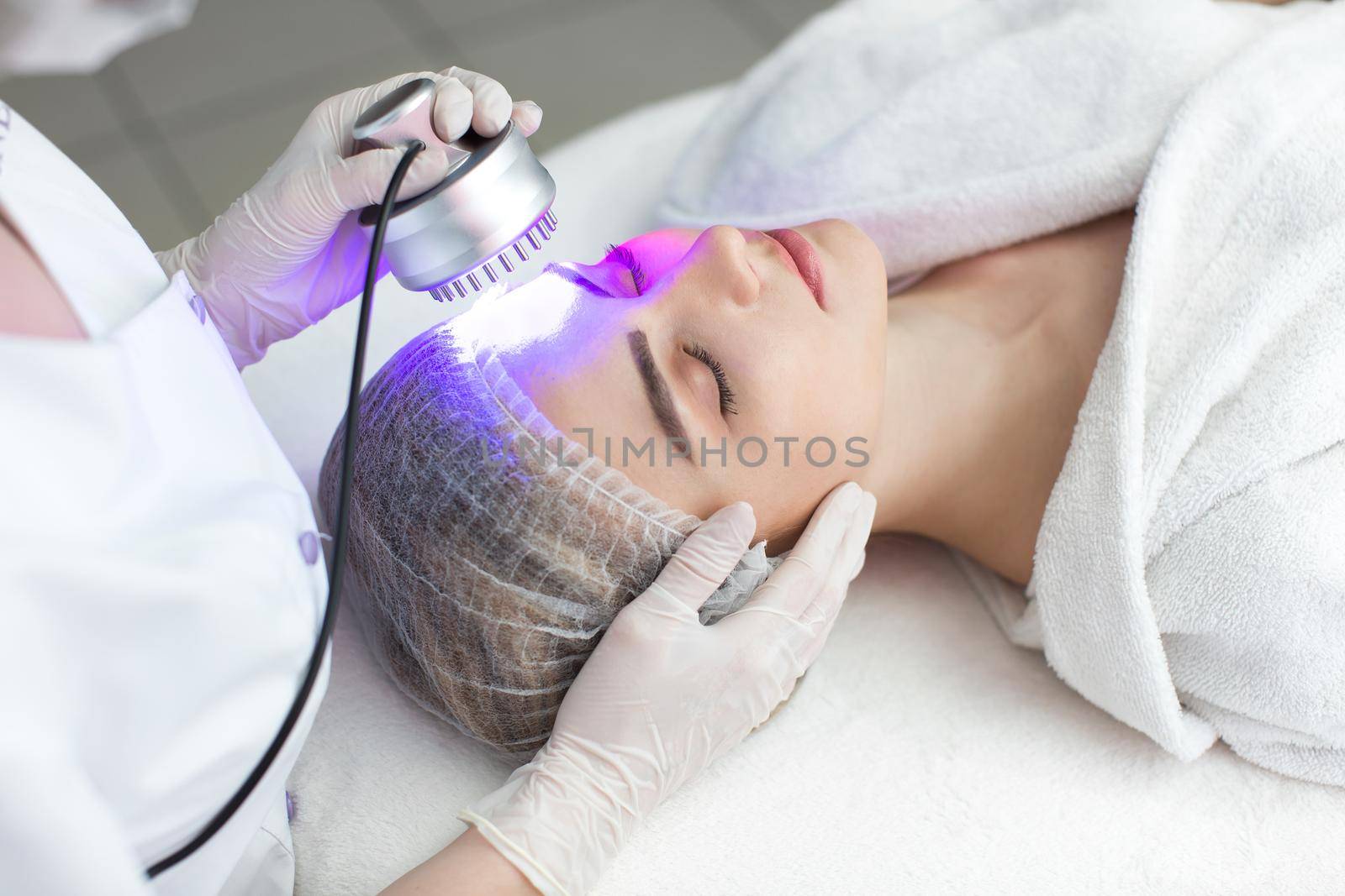 Ultrasonic massager. Light skin treatment, the woman in the beauty salon