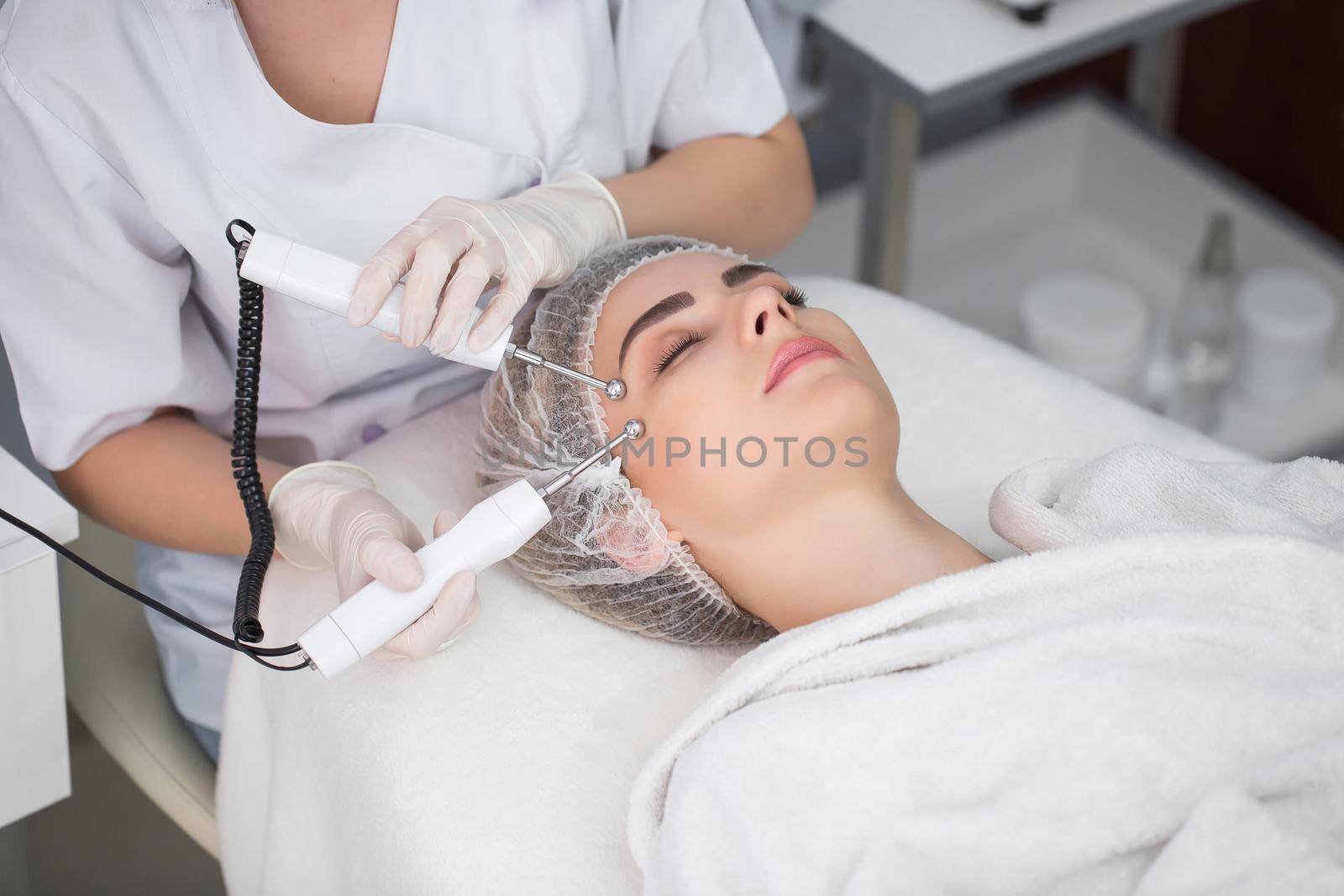 Macro close up portrait of woman having cosmetic galvanic beauty treatment in spa.Therapist applying low frequency current with electrodes on face. by StudioPeace
