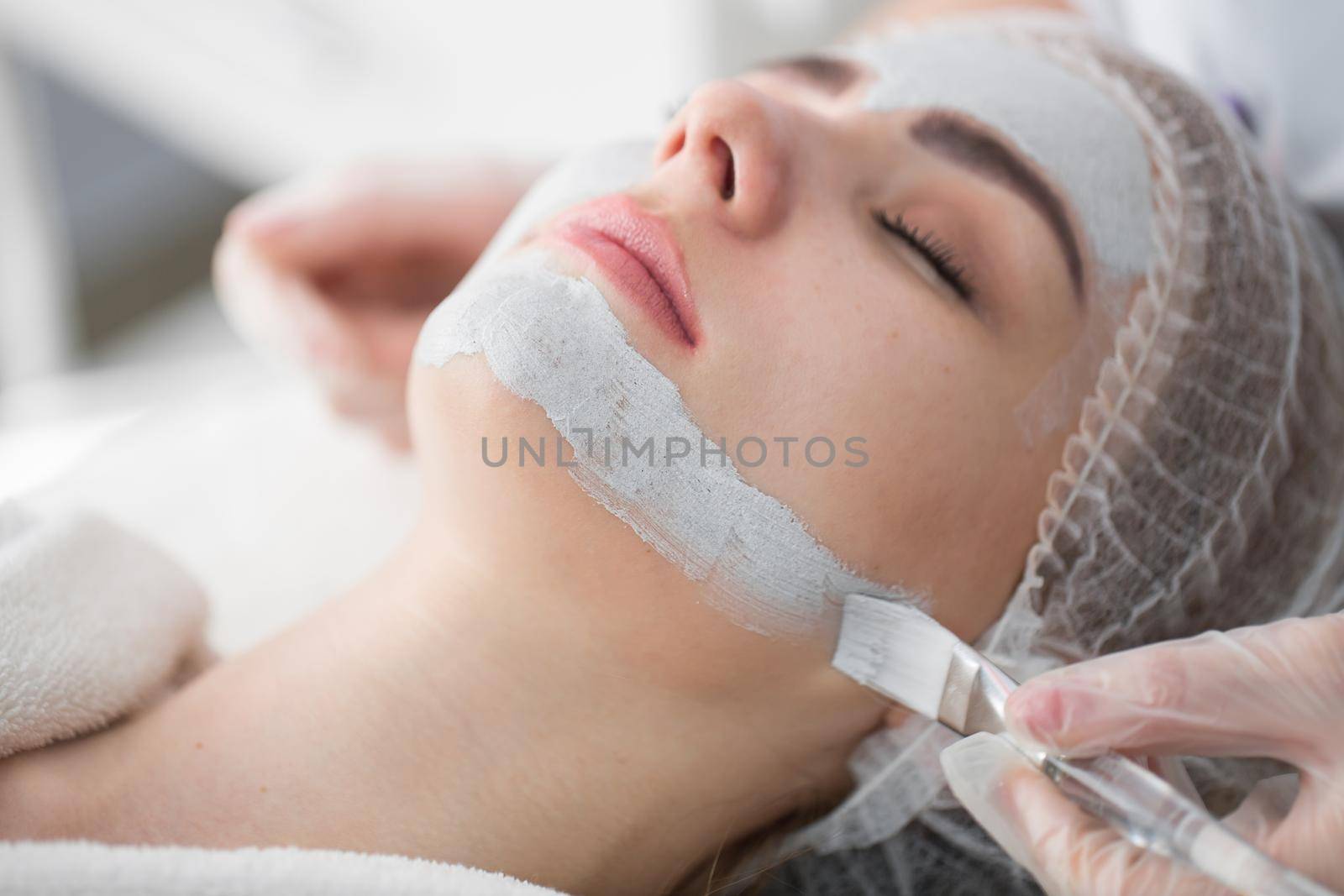 Face peeling mask, spa beauty treatment, skincare. Woman getting facial care by beautician at spa salon. by StudioPeace