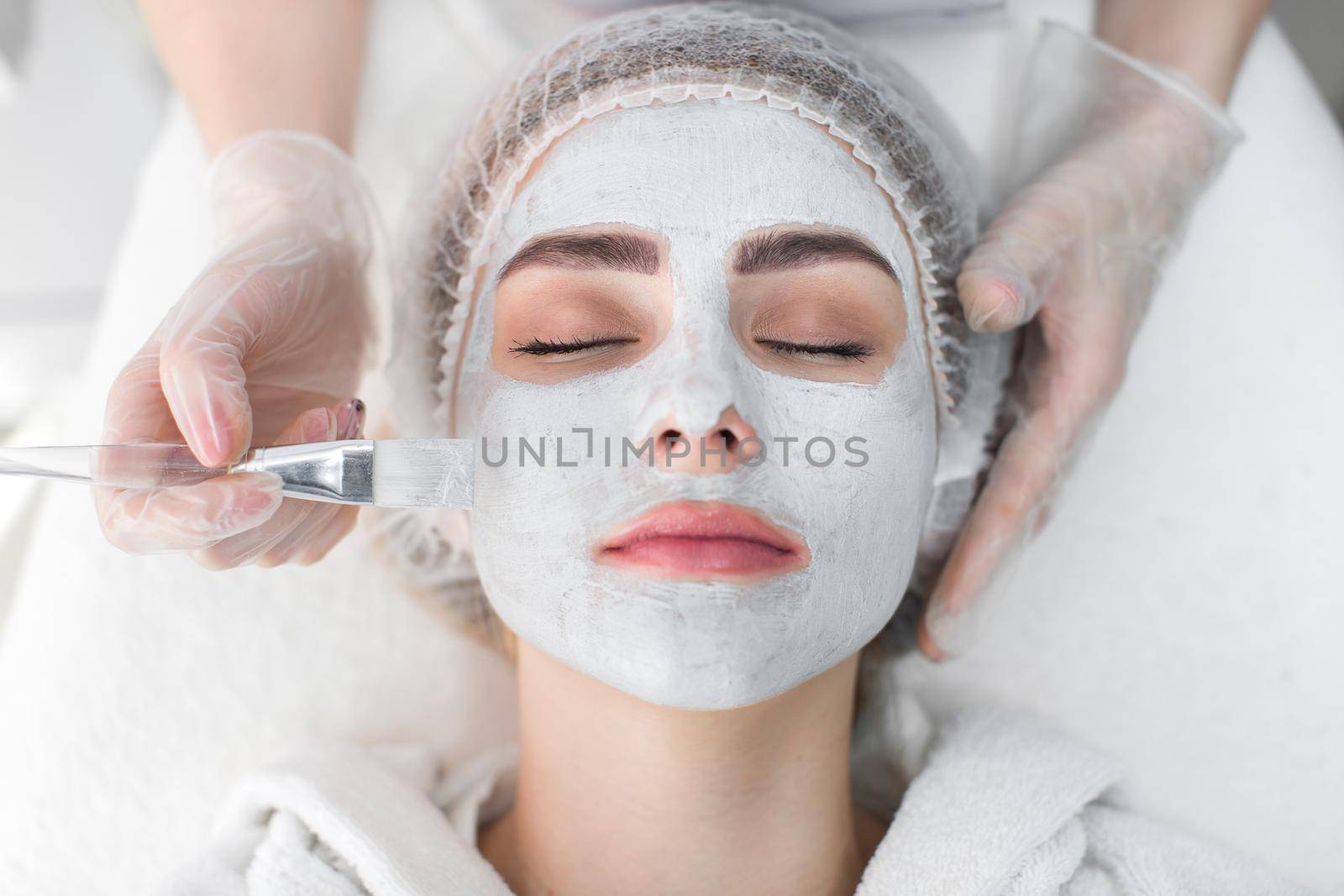 Face peeling mask, spa beauty treatment, skincare. Woman getting facial care by beautician at spa salon. by StudioPeace