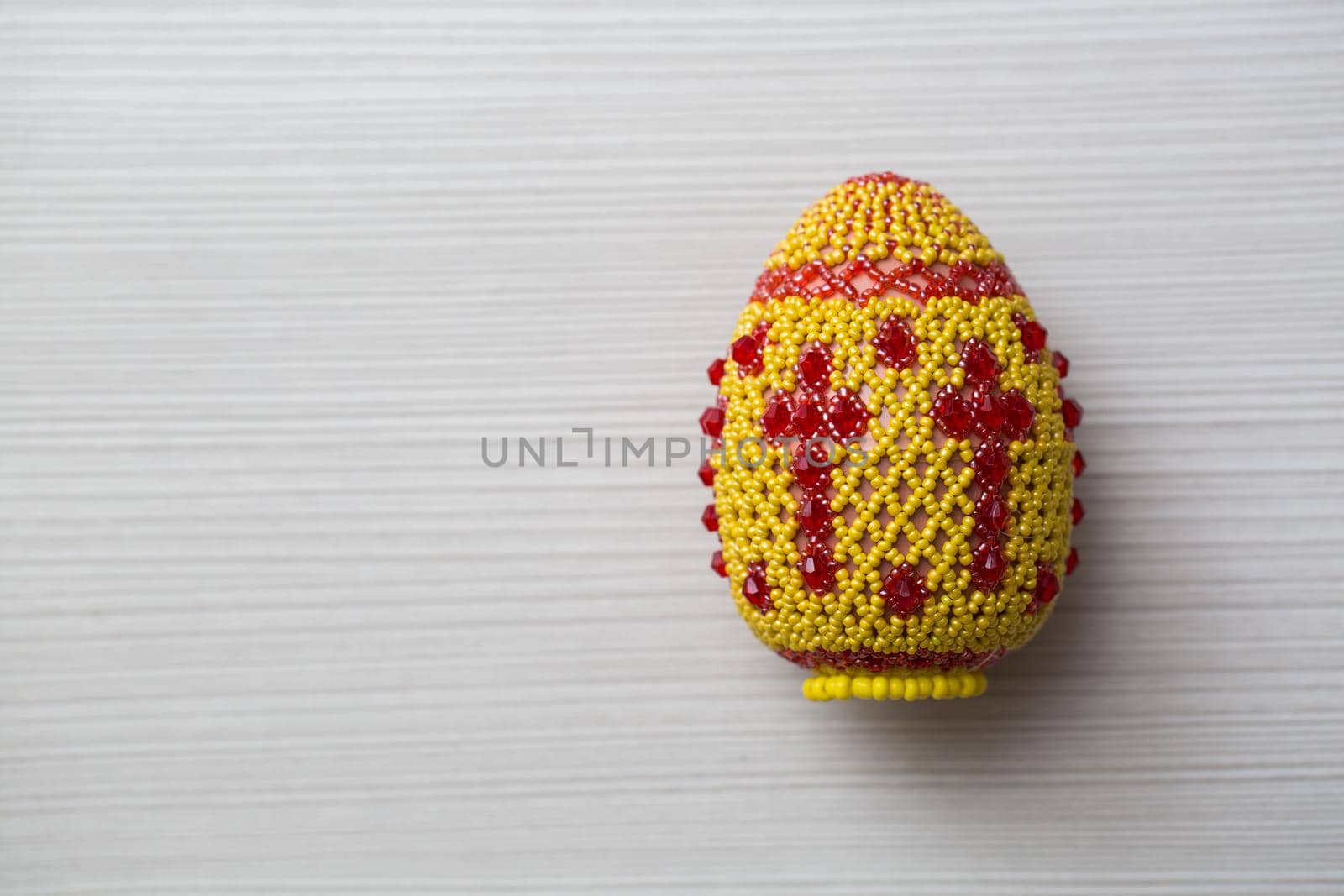 Egg decorated with small beads on a white table