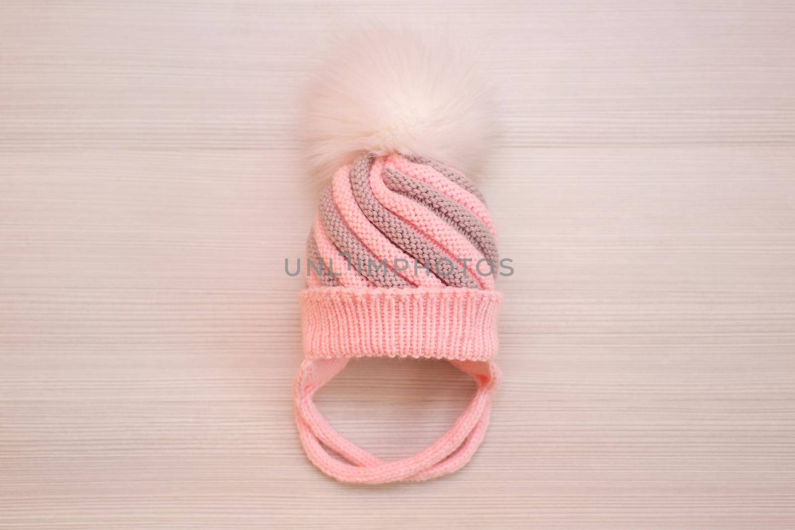 Pink children's knitted wool hat with a pompom, on a white background. by StudioPeace