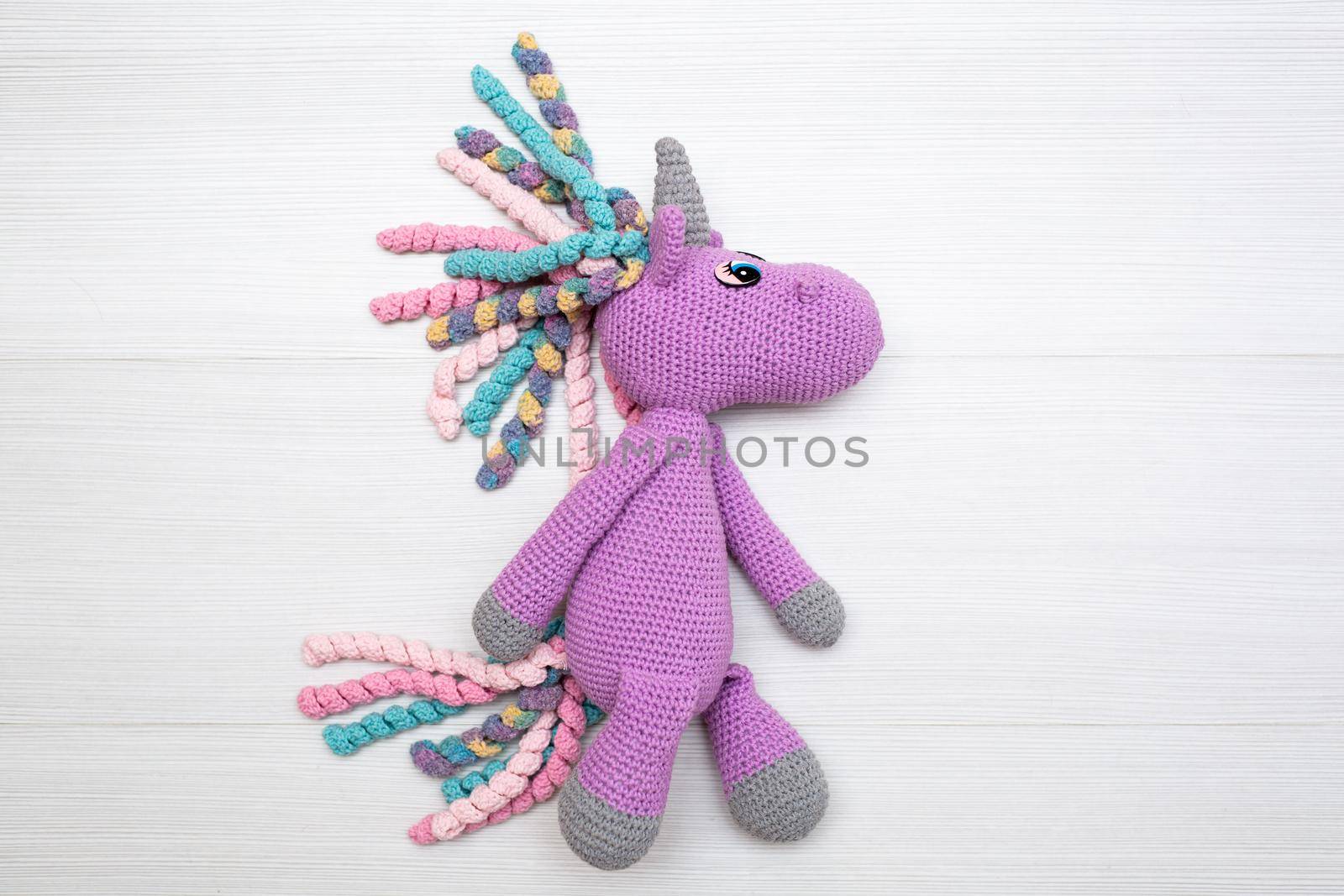 A knitted unicorn with a multicolored mane. A toy for a child by StudioPeace