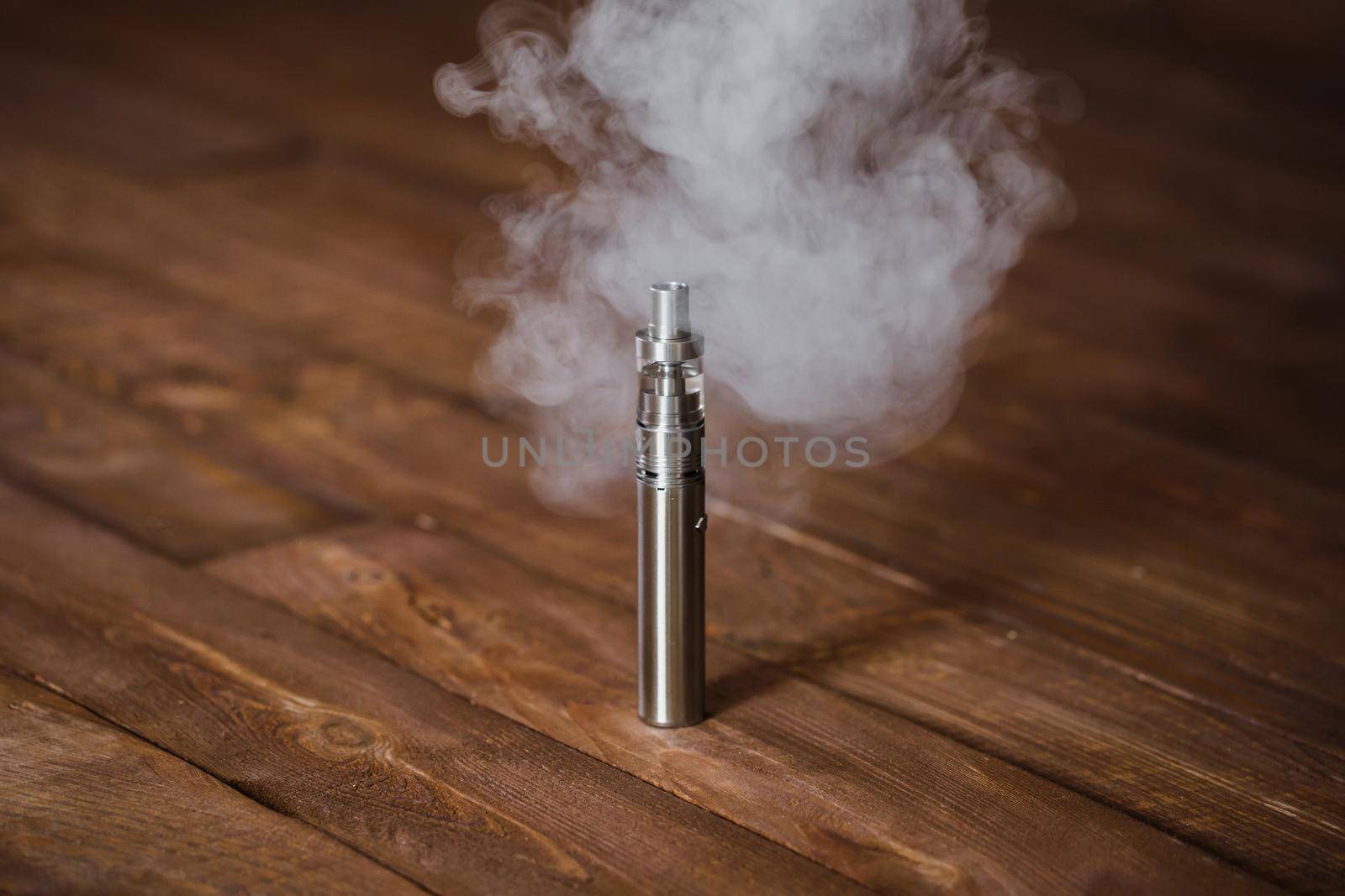 Electronic cigarette on a wooden table. Smoke.