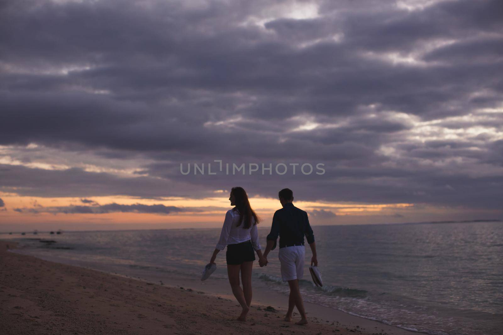 Young couple enjoying the sunset on the beach. by StudioPeace