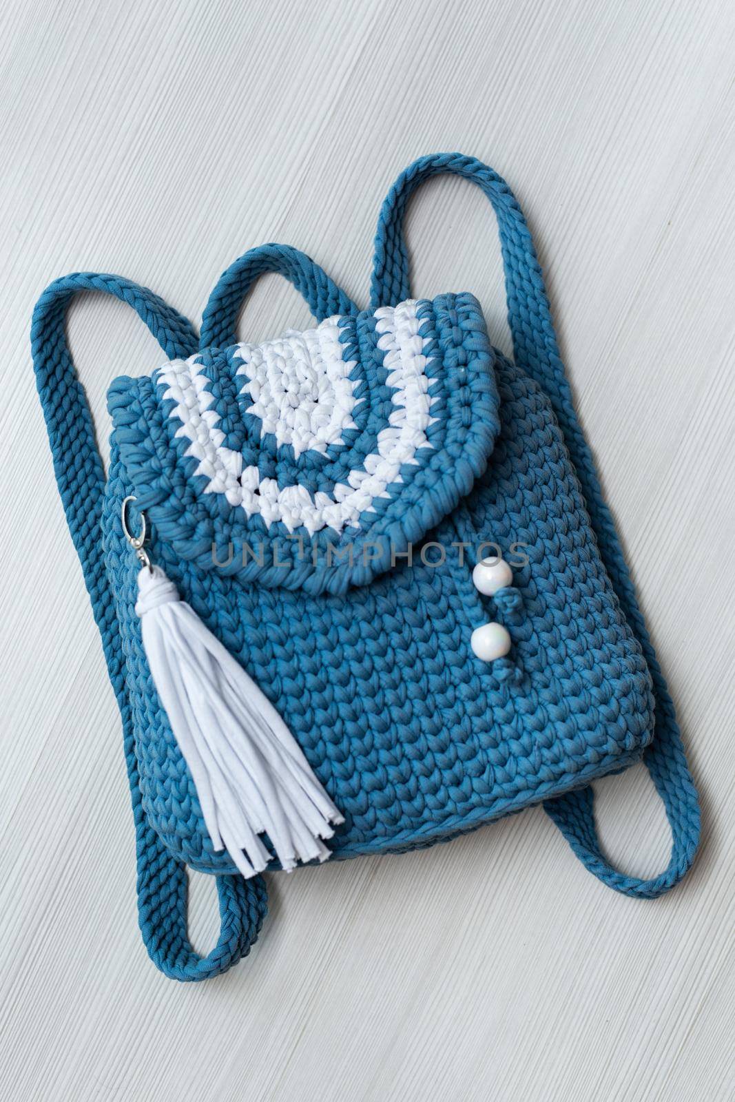 Small knitted blue backpack on a white background. by StudioPeace