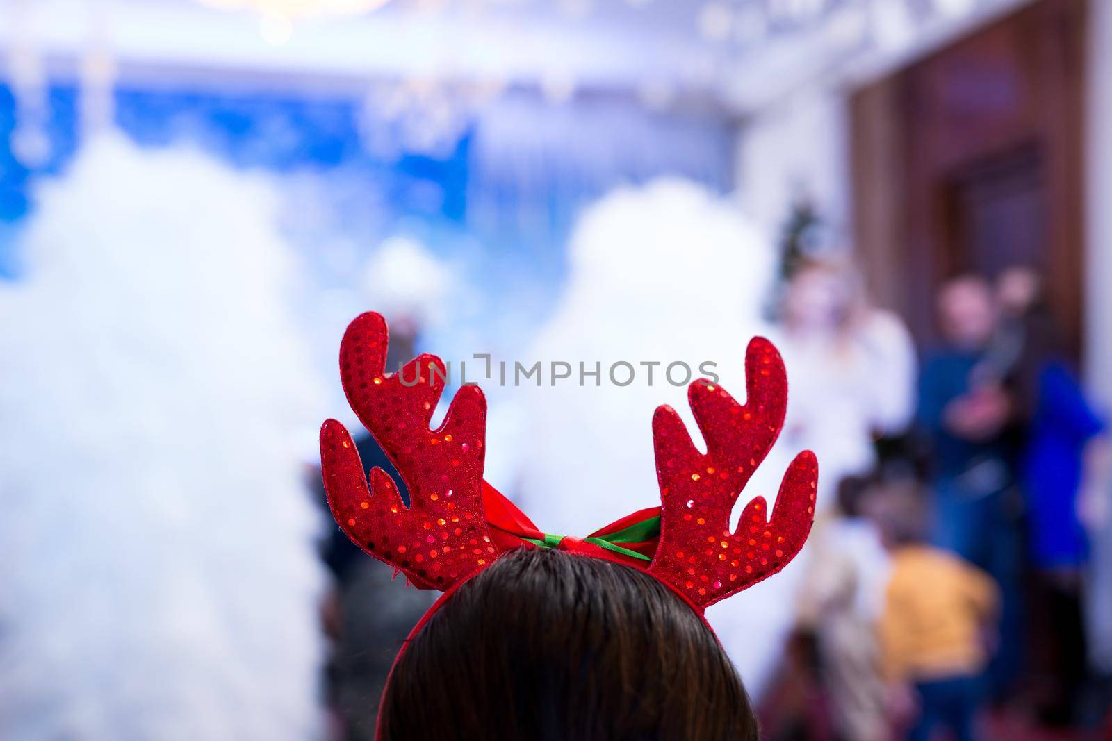 Young woman wearing antler deer headband. Rear view.