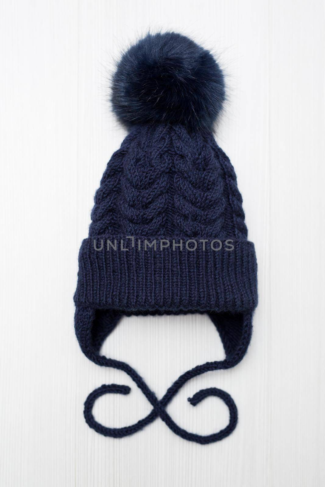 Children's knitted wool hat with a pompom, on a white background