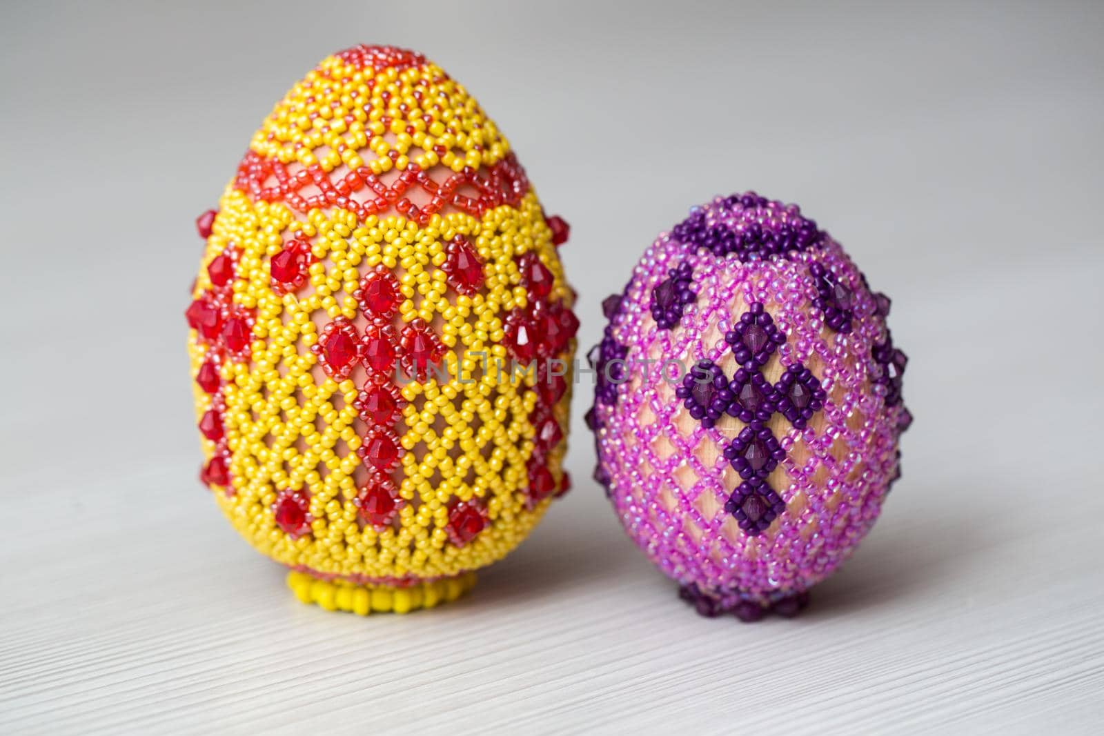 Eggs decorated with small beads on a white table. by StudioPeace