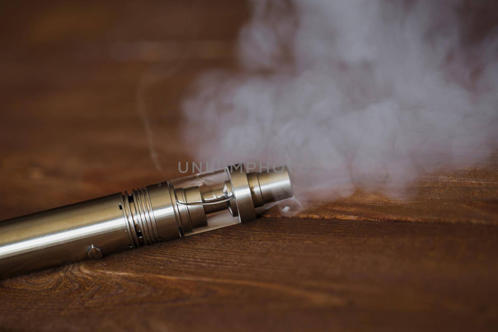 Electronic cigarette on a wooden table. Smoke.