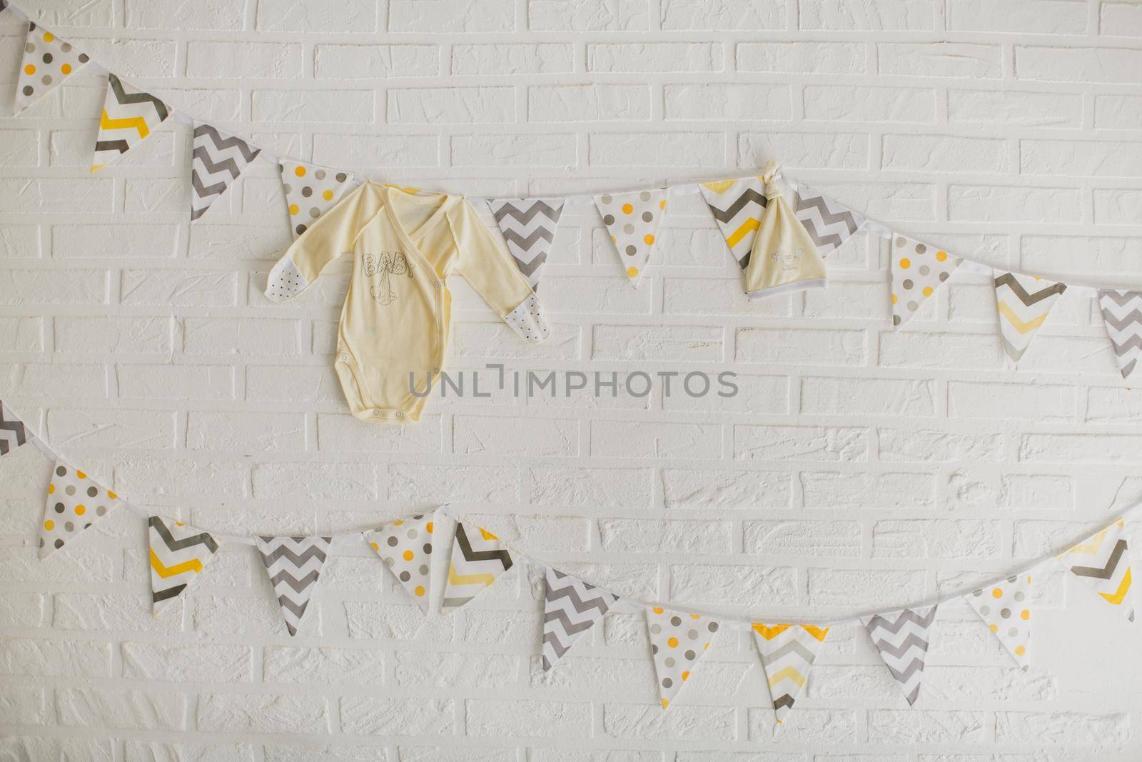 Flags and clothes of a baby hanging on a white stone wall in the Studio