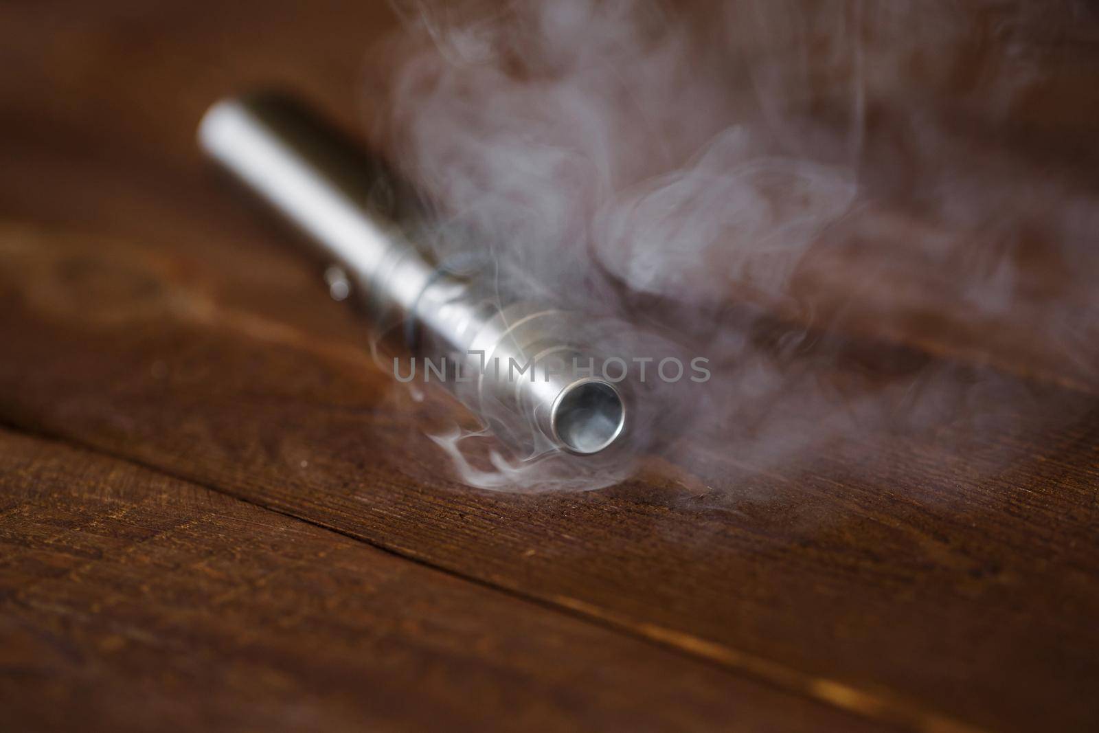 Electronic cigarette on a wooden table. Smoke.