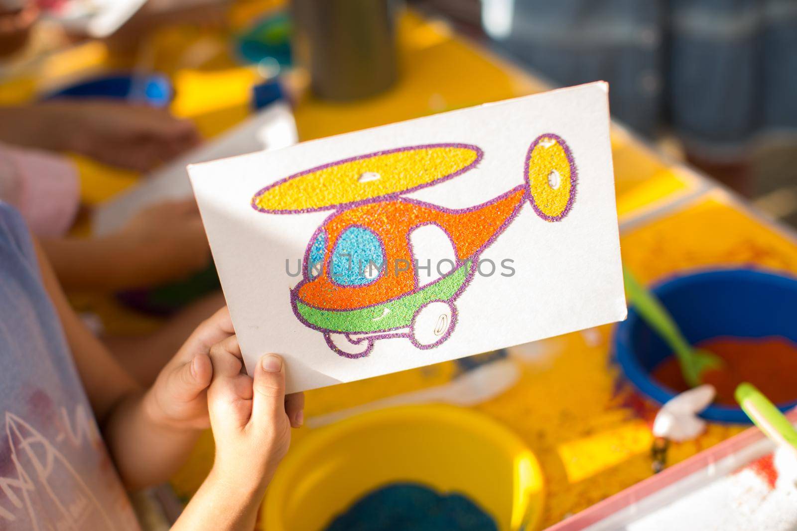 A child draws with colored sand picture. Cartoon characters by StudioPeace