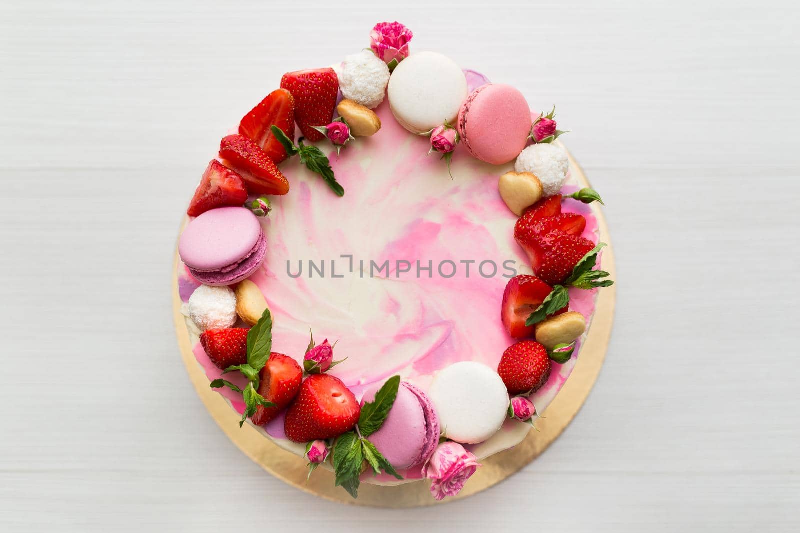 Beautiful cake with strawberries and macaroons on a white table