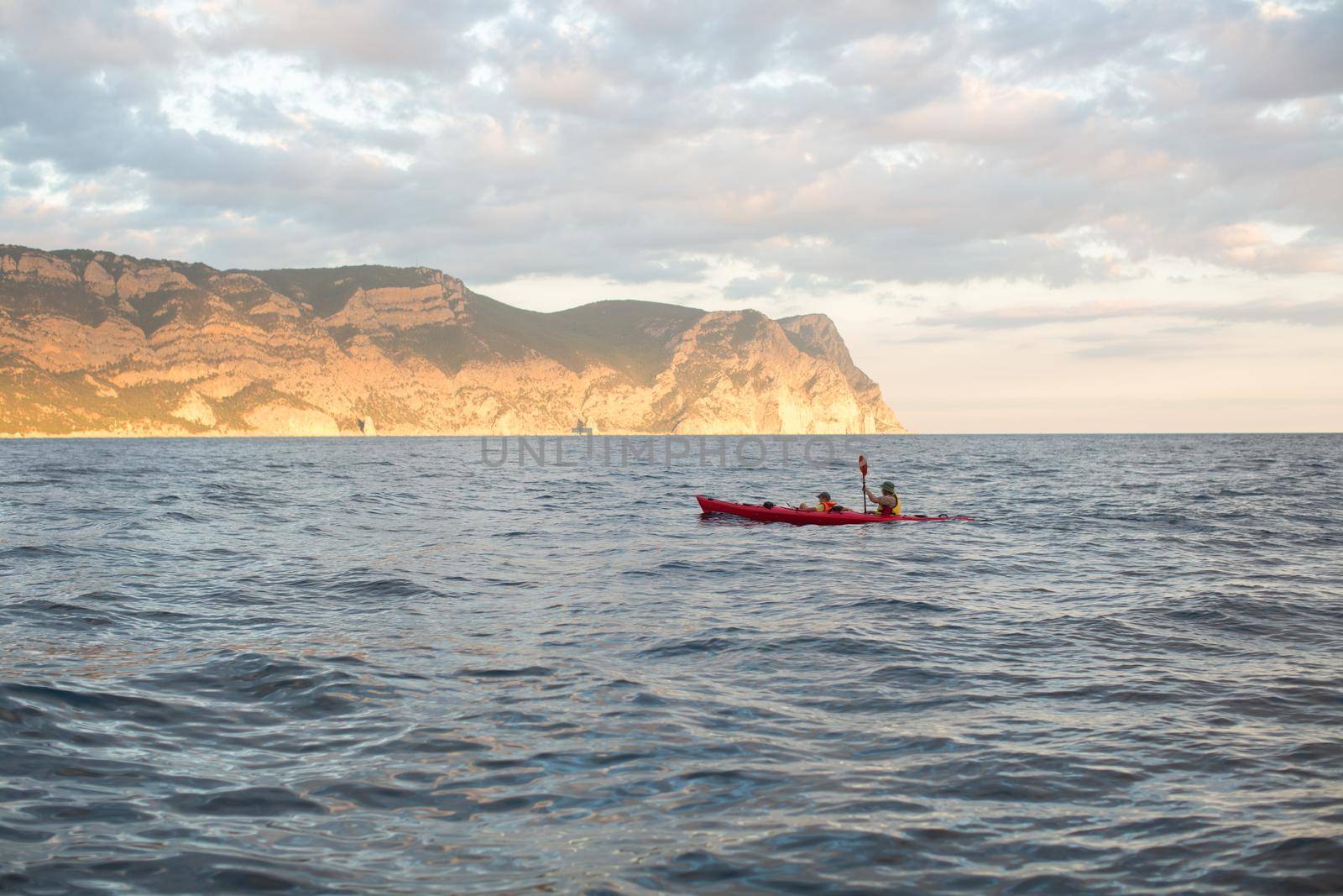 Kayaks. Canoeing in the sea near the island with mountains. People kayaking in the ocean.