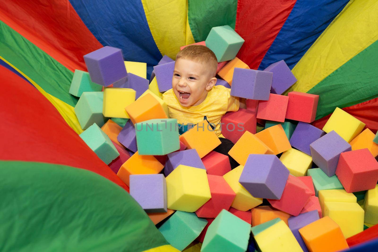 A boy plays in a playground with cubes. Foam dry pool. A boy builds a castle from cubes.