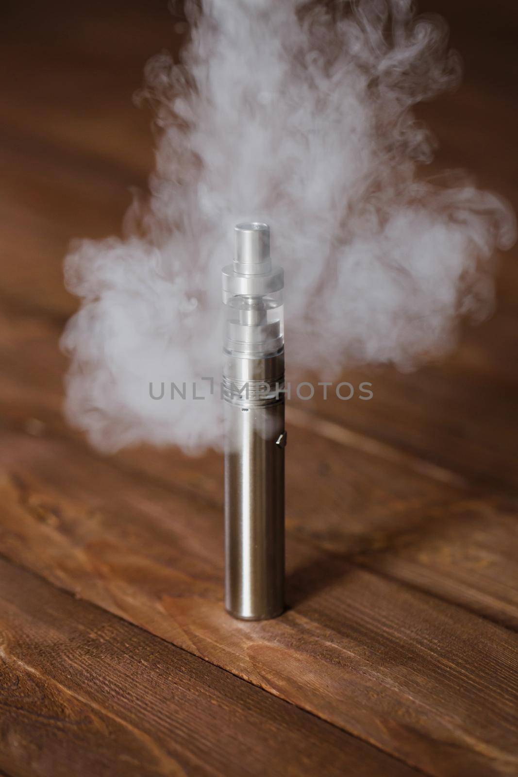 Electronic cigarette on a wooden table. Smoke by StudioPeace