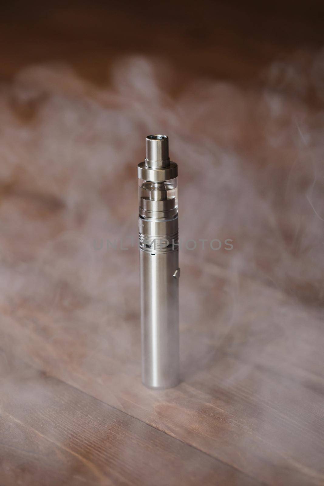 Electronic cigarette on a wooden table. Smoke by StudioPeace