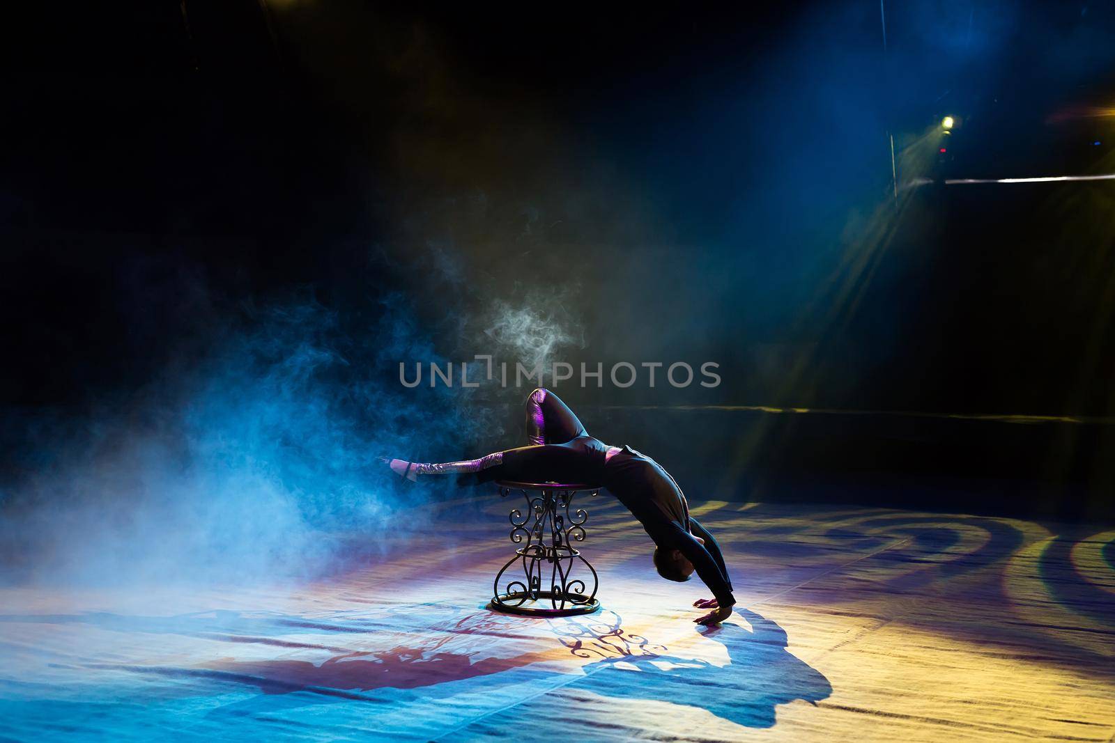 Acrobat performs a difficult trick in the circus by StudioPeace