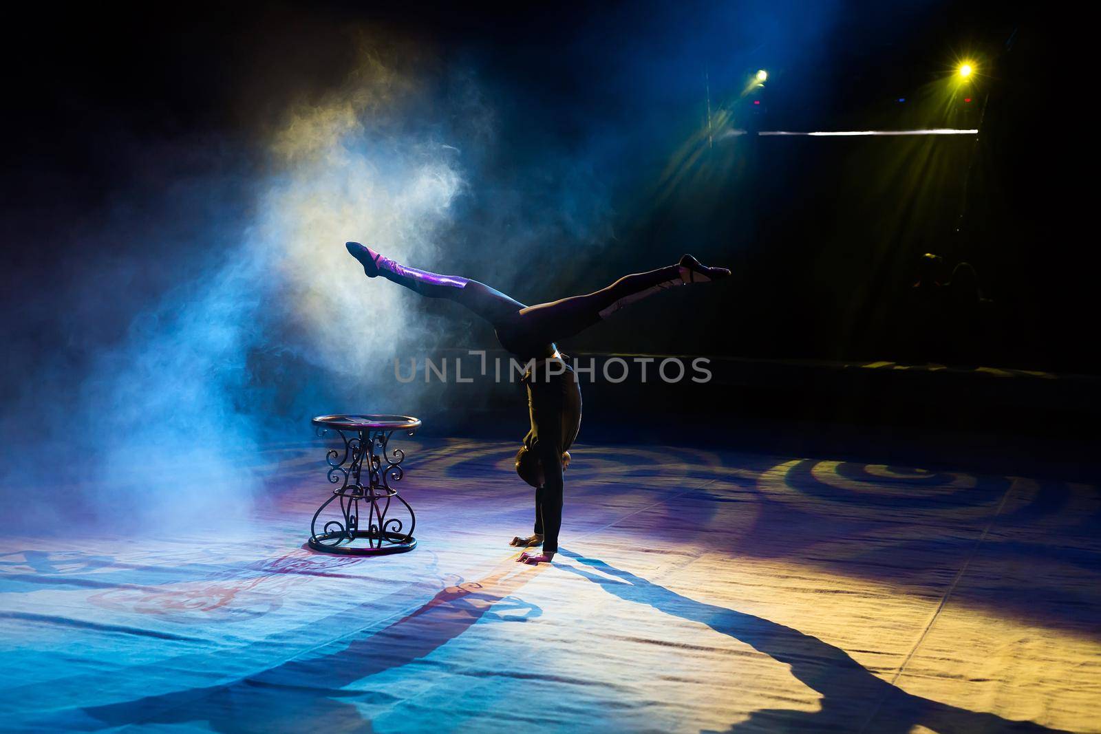 Acrobat performs a difficult trick in the circus by StudioPeace