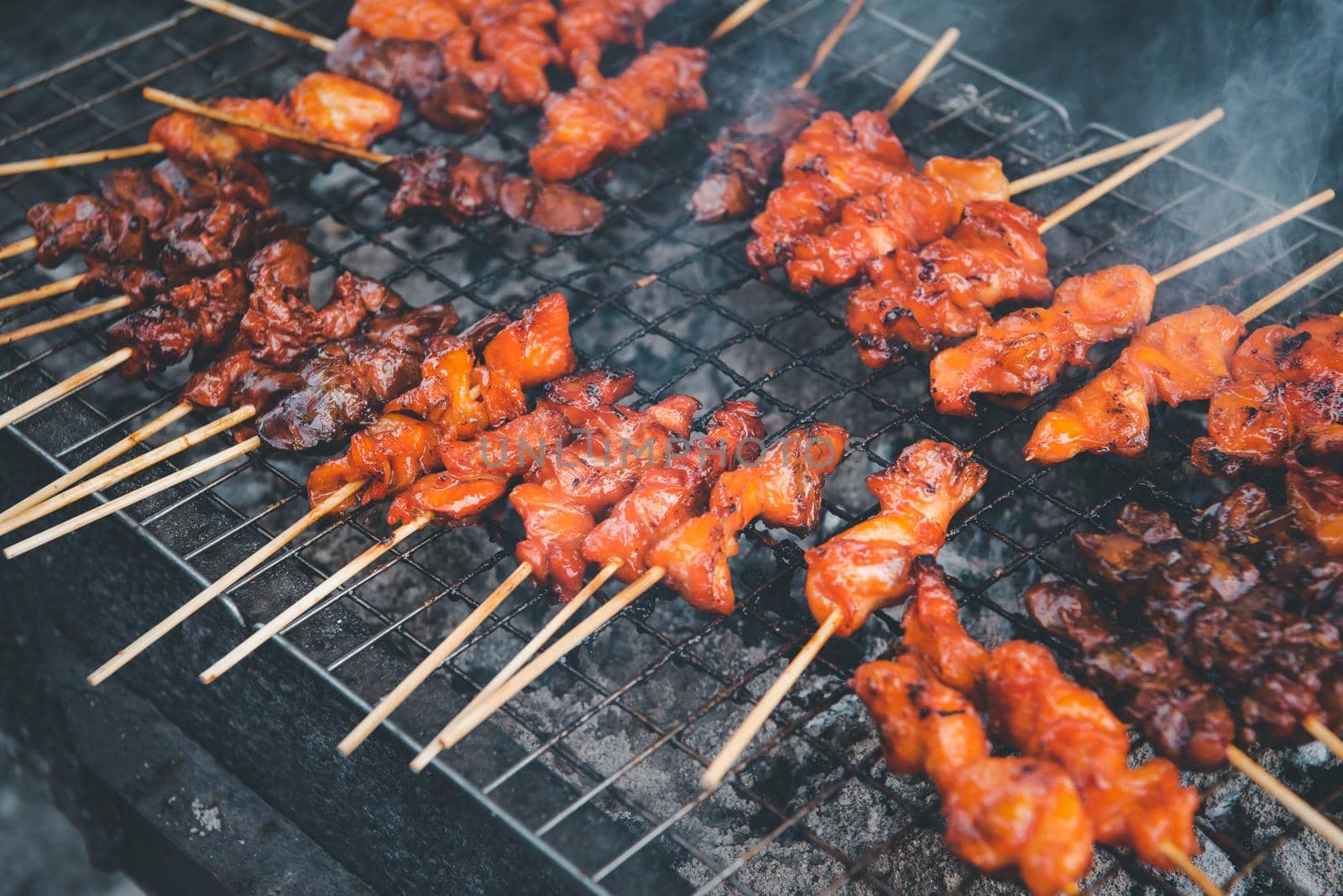 Grilled chicken sauce is a Thai barbeque food by chicken and sauce cooking on charcoal with flames at Thai street food market