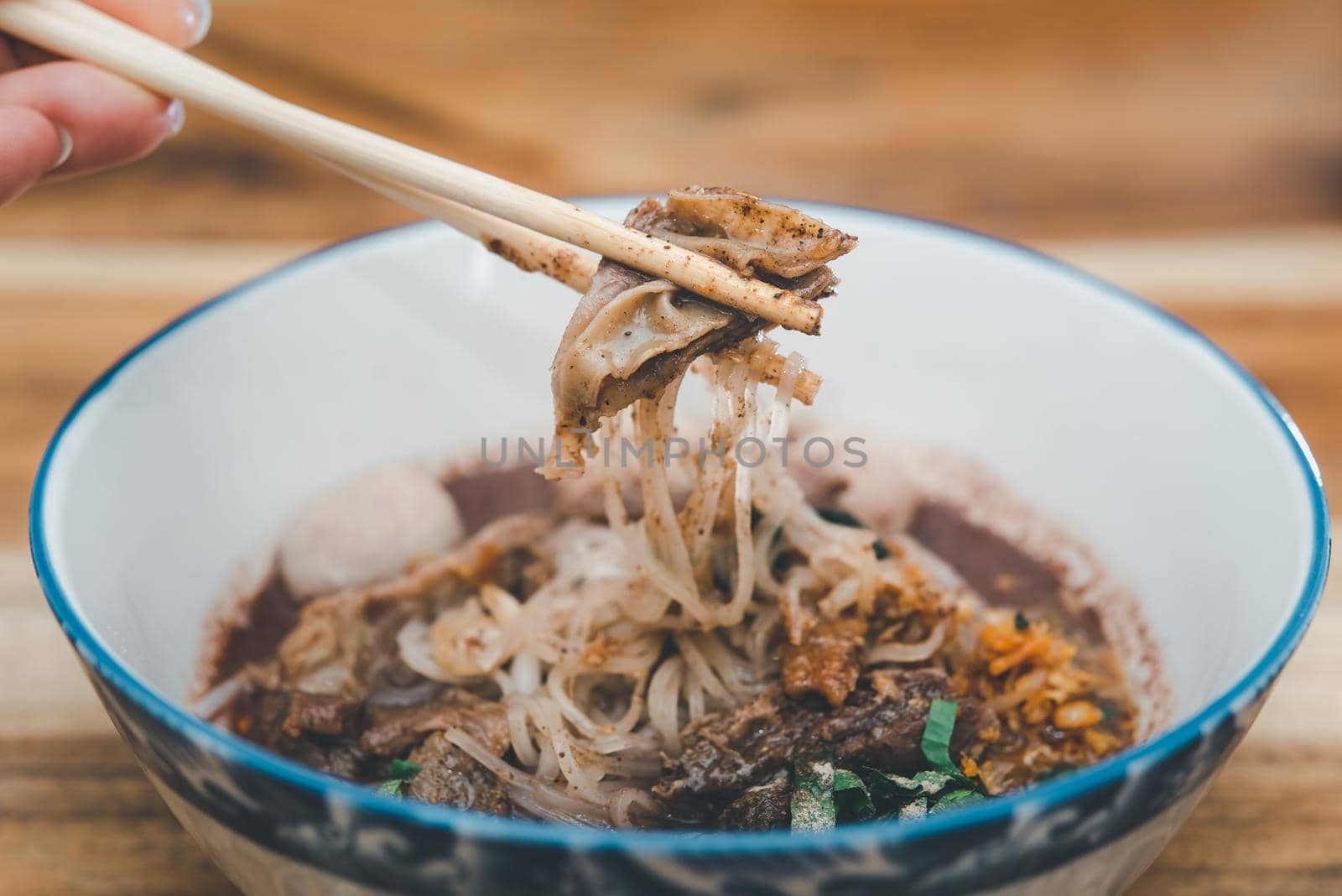 Braised beef clear noodle with meat balls soup stew (Ekaehla meat) with vegetable in bowl for sale at Thai street food market or restaurant in Thailand