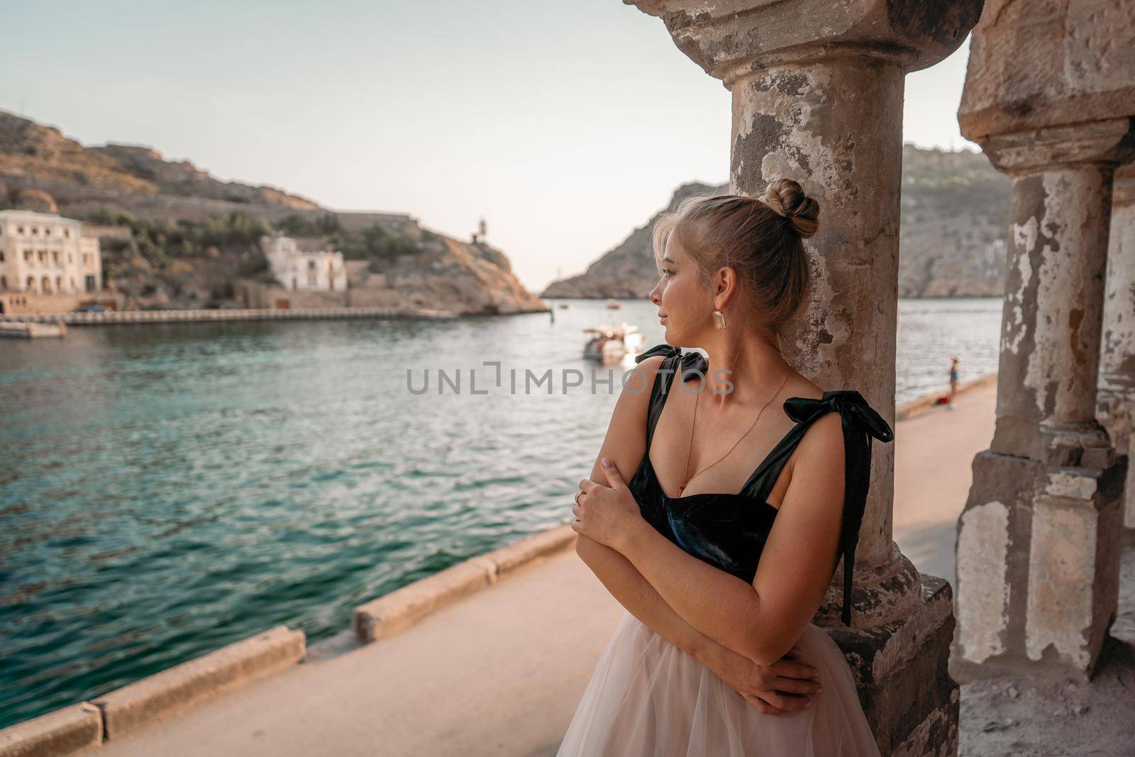 Side view portrait of a relaxed woman breathing fresh air at the seaside. She stands near the old column